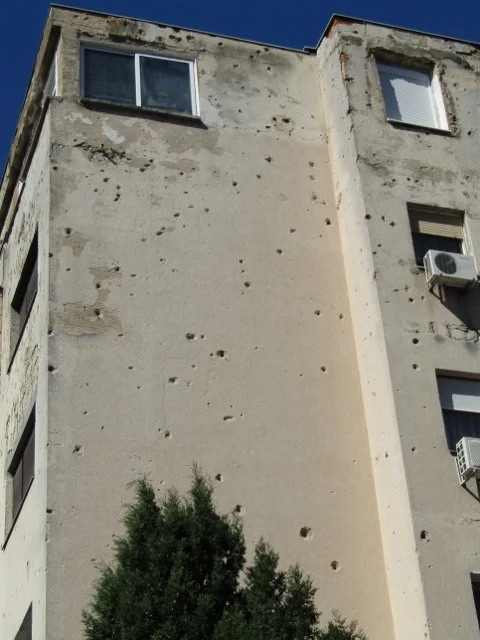 This apartment building is still occupied by tenants, there is no funds to repair the war damage and large bullet holes.