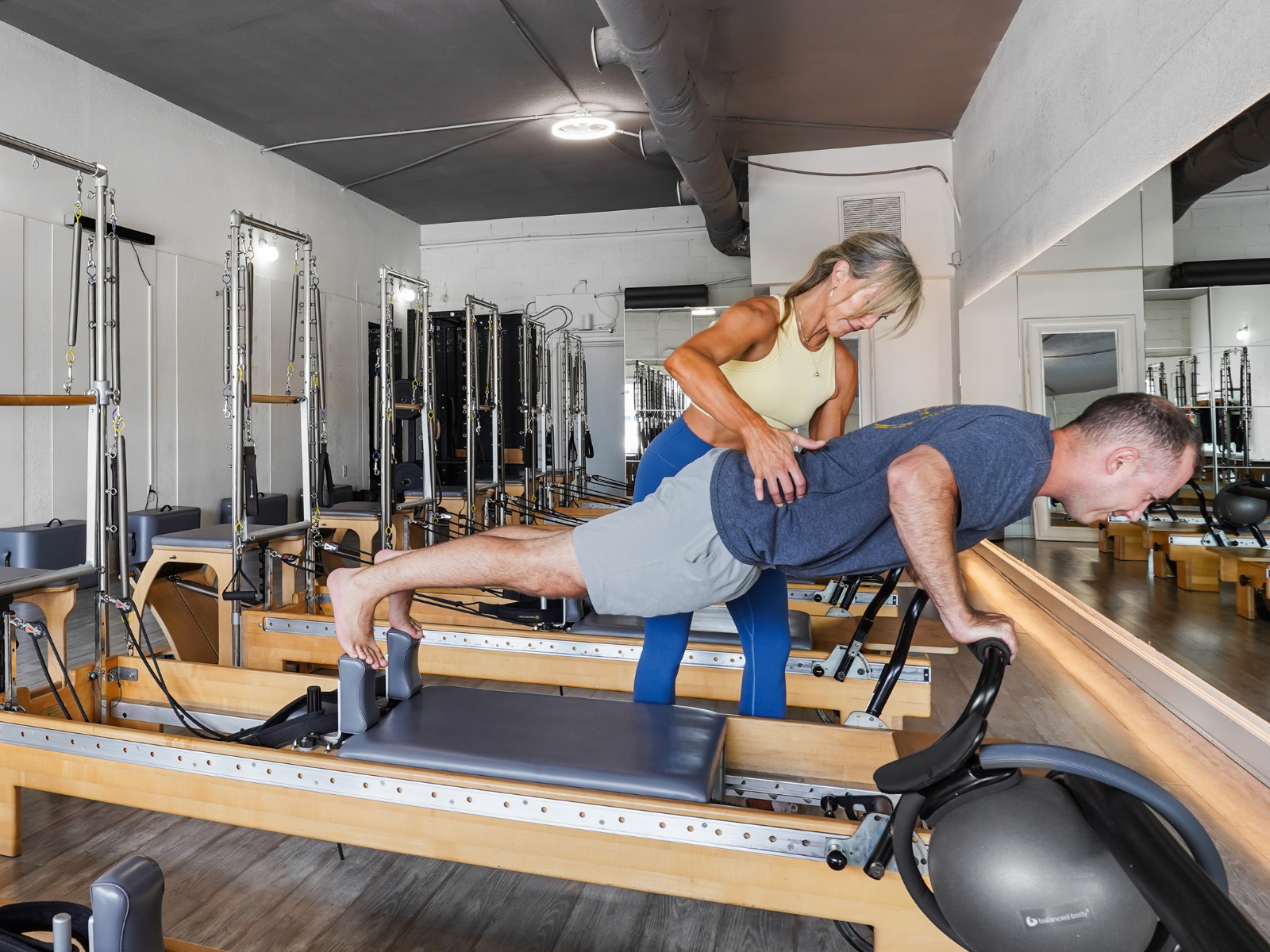 Certified Pilates instructor coaching a male client through an advanced reformer exercise at Pilates on Third, a strength-focused Pilates studio in Jacksonville Beach.