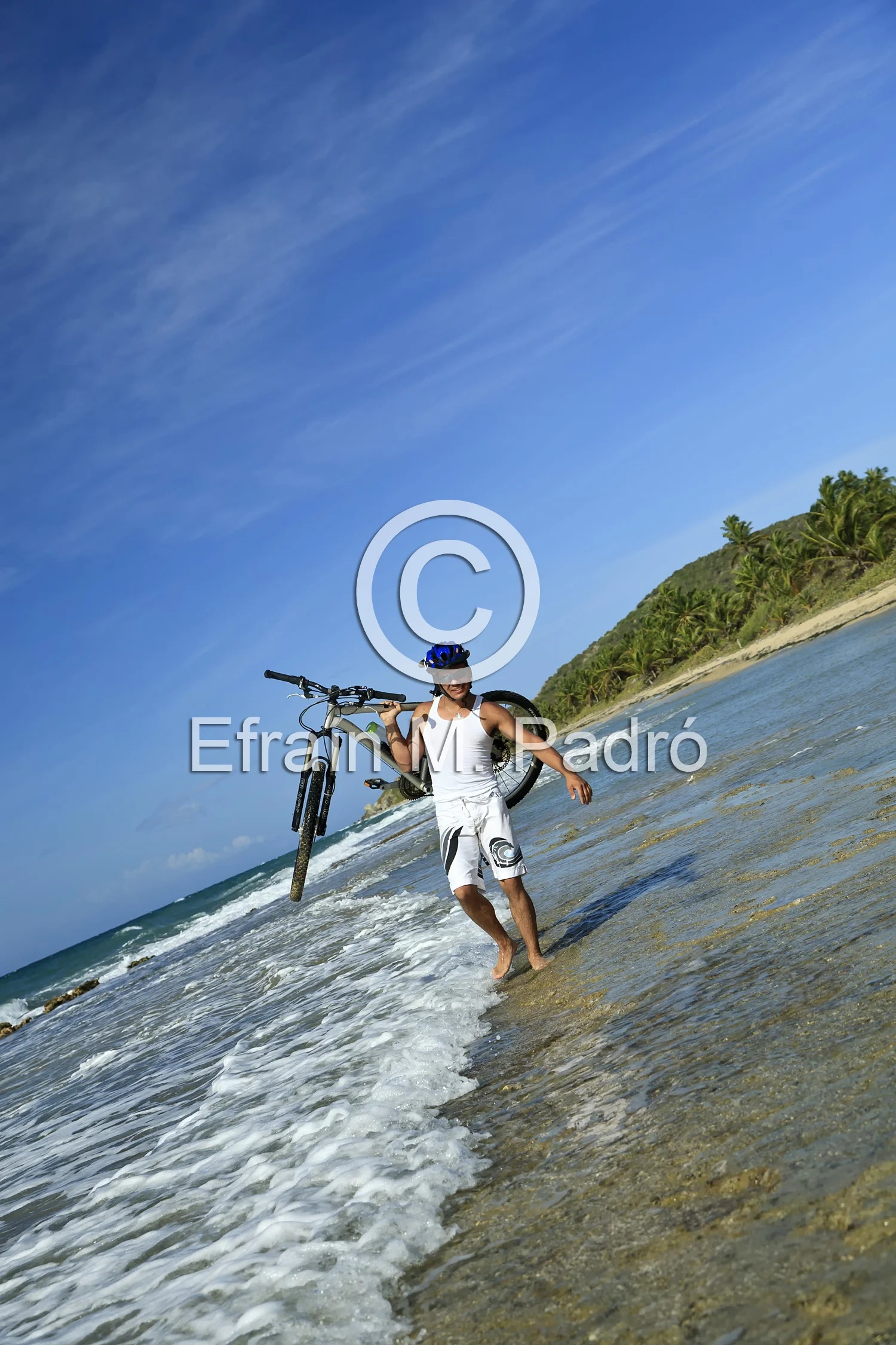 Mountain biker carrying bike on beach, Vieques, Puerto Rico