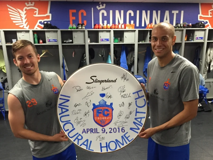 Antoine Hoppenot and Luke Spencer holding up the inaugural drum head after the entire team signed it.