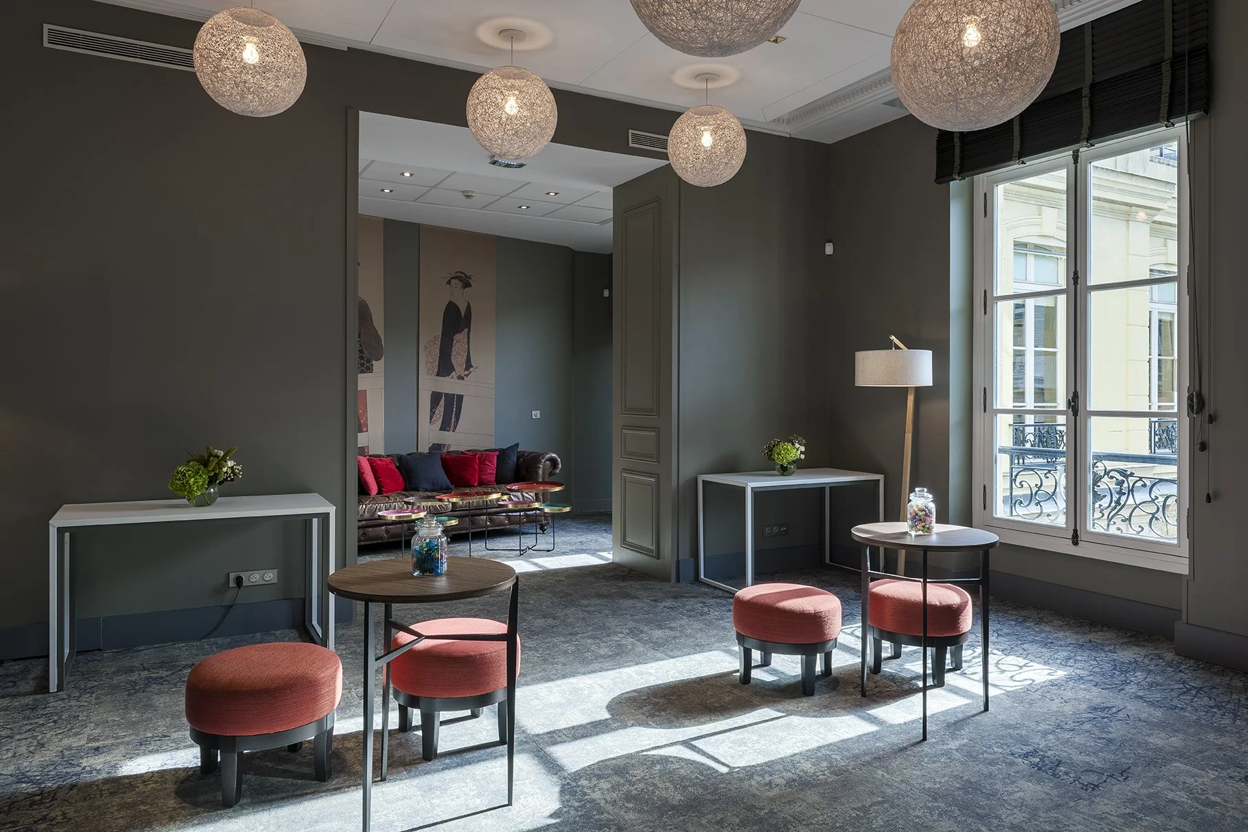 Intérieur d'une salle de meeting lumineuse avec meubles modernes, un canapé en cuir, table basse, lampes, décorations florales, et une grande fenêtre laissant entrer la lumière naturelle, Cercle d'Aumale, hôtel particulier, Paris, Location, Prestige,