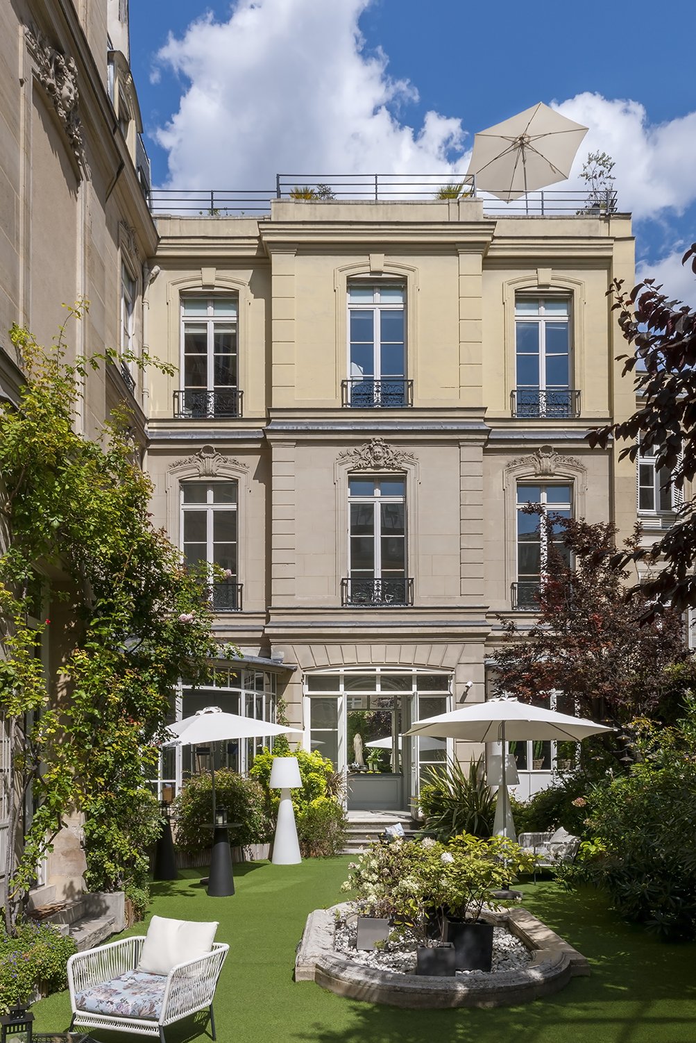 Cour arrière d'un immeuble haussmannien avec jardin, parasols, mobilier de jardin, arbres et ciel bleu avec quelques nuages, Cercle d'Aumale, hôtel particulier, paris, Location, prestige, luxe, Dalida,
