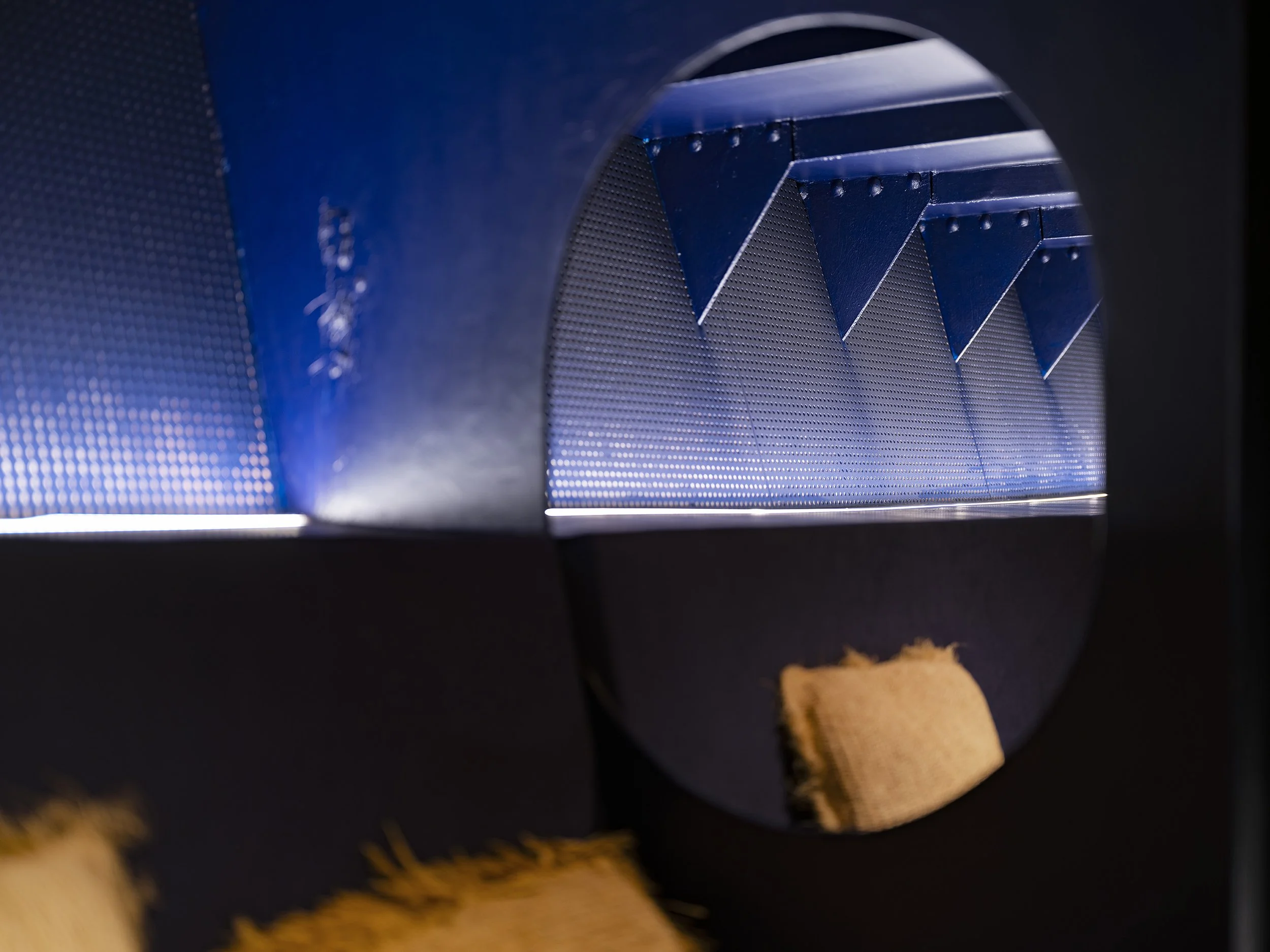 des éléments métalliques bleus et des détails circulaires, vue par un trou dans une surface noire,  Bateau Phare, Paris, Concert, Nightlife, Space Invaders, Mosaïc, Bar, Food, terrasse, quai de Seine, longe, chill