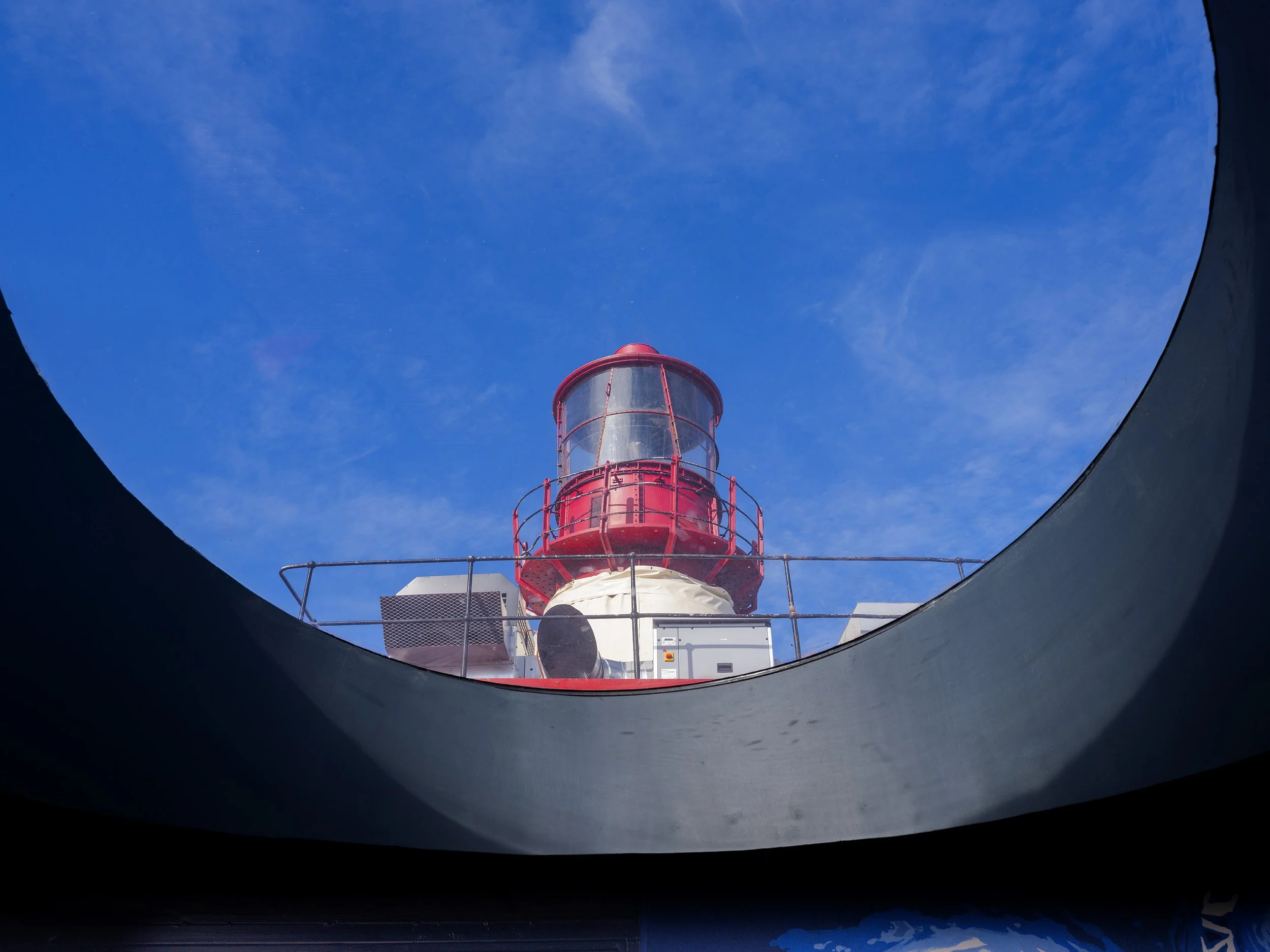 Vue de l'intérieur d'une structure circulaire regardant vers le haut une tour de surveillance rouge en acier, avec un ciel bleu en arrière-plan, Bateau Phare, Paris, Concert, Nightlife, Space Invaders, Mosaïc, Bar, Food, terrasse, quai de Seine,