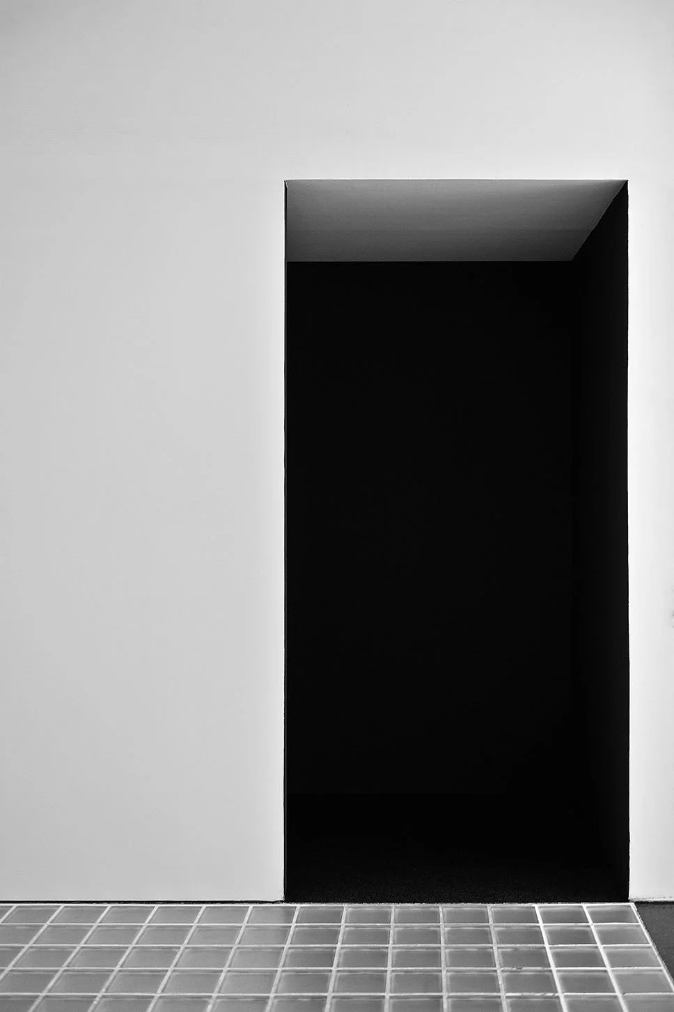 Une porte encastrée noire dans un mur blanc, avec un sol en carreaux grisés, MACBA, Art Modern, Barcelone, Art Contemporain,
