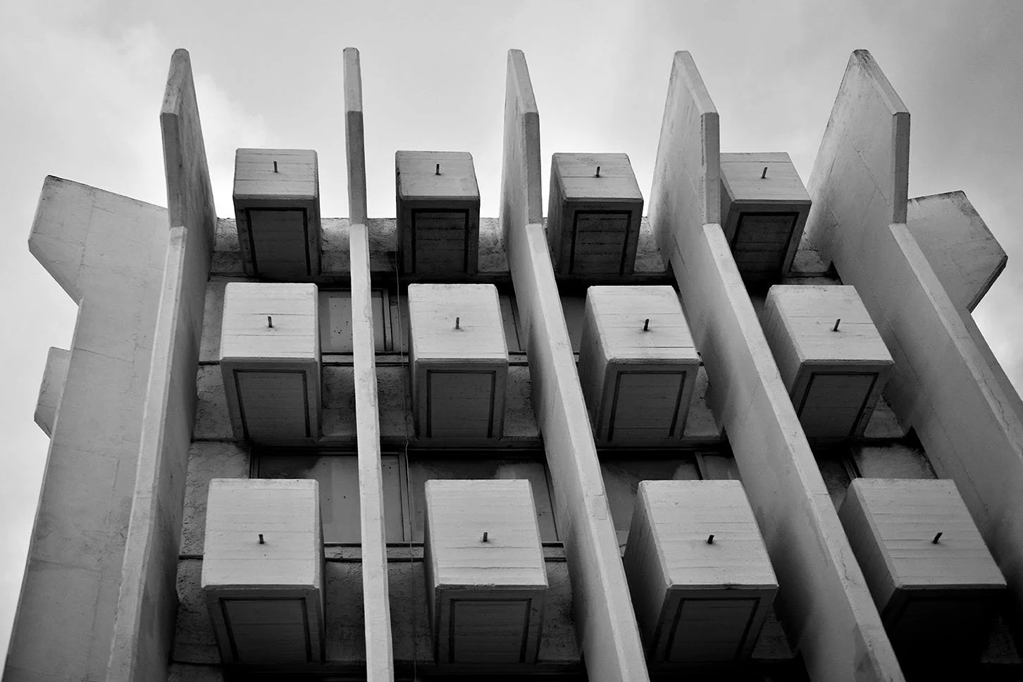 Vue en contre-plongée d'un bâtiment en béton brutaliste avec des balcons en retrait apparents, en noir et blanc. architecture, Rhodes, Grèce,
