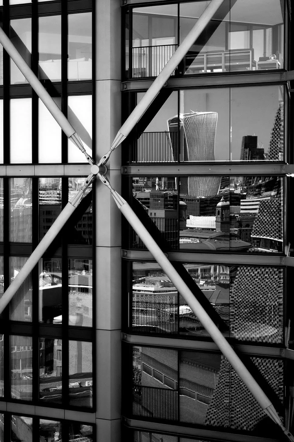 Face d'un bâtiment moderne en verre, avec des diagonales métalliques croisant la façade, offrant des reflets urbains dans les fenêtres. Londres, UK, Angleterre, Tate Modern,
