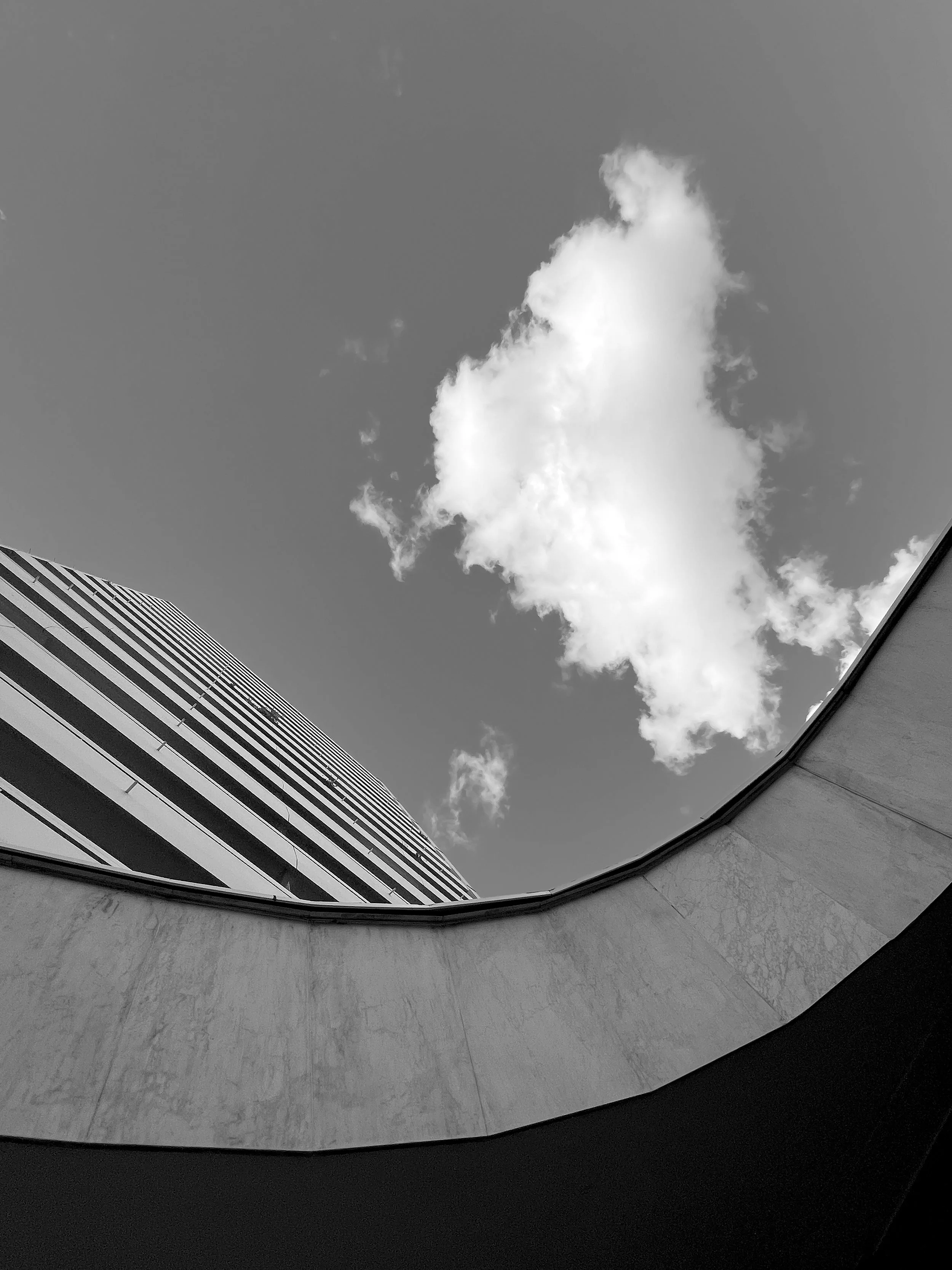 Vue en contre plongée d'un bâtiment moderne avec plusieurs étages et fenêtres vitrées, le tout sous un ciel nuageux. Architecture, Paris, nuage, France,