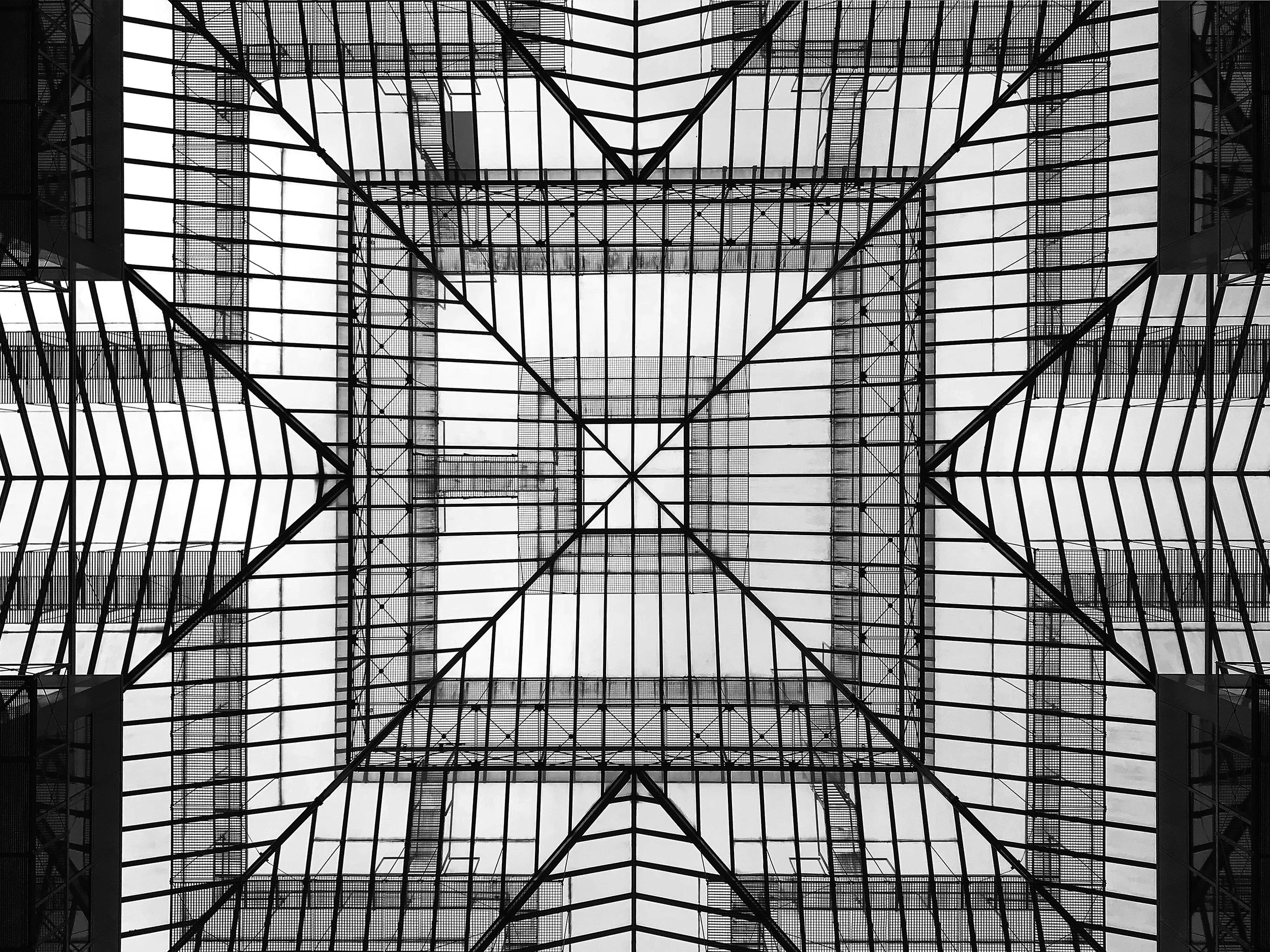 Vue en contre-plongée d'une structure en verre et en métal d'un bâtiment, montrant un plafond en grille avec un motif symétrique. Architecture, London,