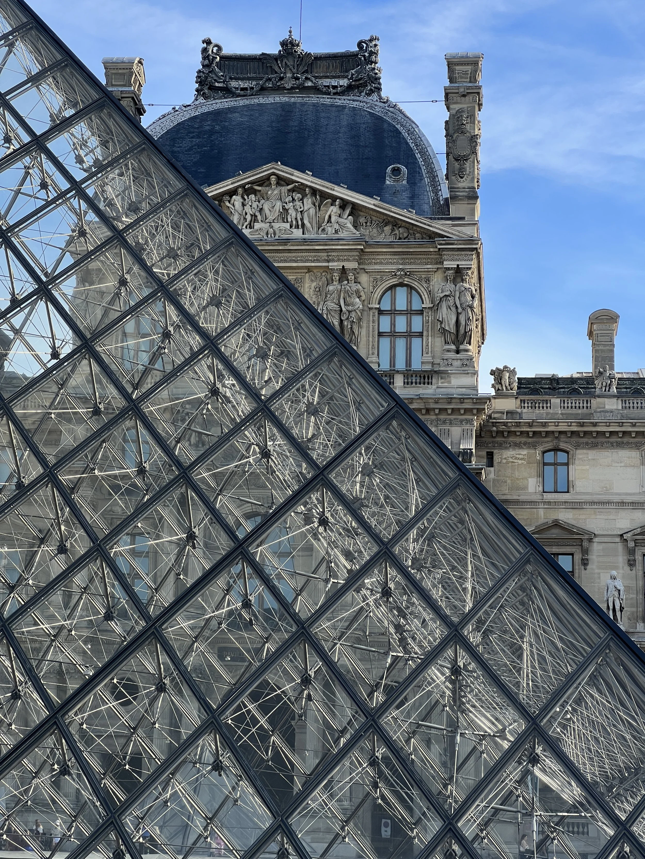 Vue de la pyramide en verre du musée du Louvre avec le bâtiment historique en arrière-plan, sculptures décoratives et ciel bleu, Paris, France, architecture, Leoh Ming Pei, 