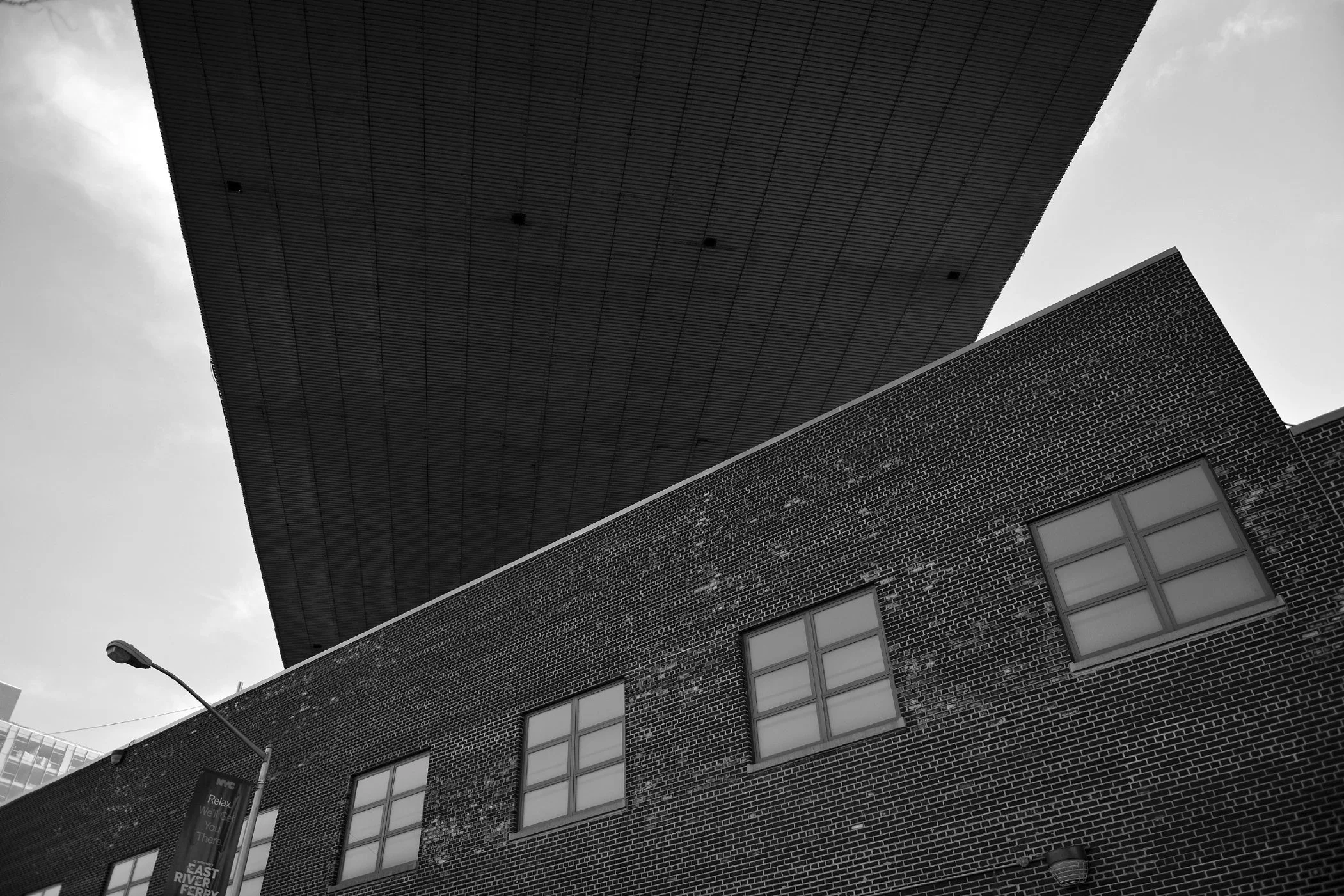 Vue en contre-plongée d'un bâtiment en briques avec plusieurs fenêtres, avec une structure en haut et un lampadaire au premier plan. architecture, Tablier du pont de Brooklyn, New-York, U.S.A. Brooklyn,