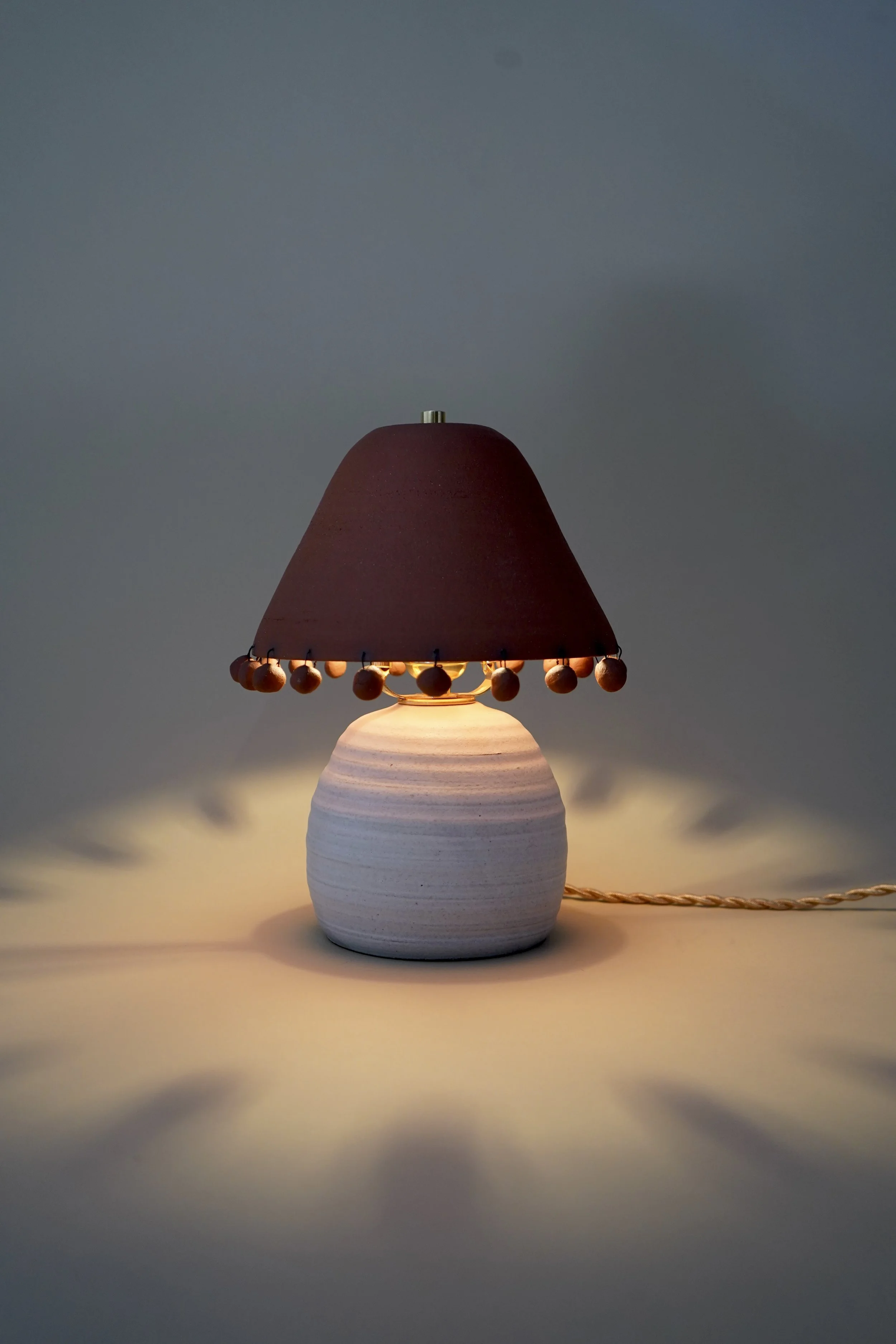 Handmade two-tone ceramic table lamp with white stoneware base, terracotta shade, and hand-rolled ceramic beads
