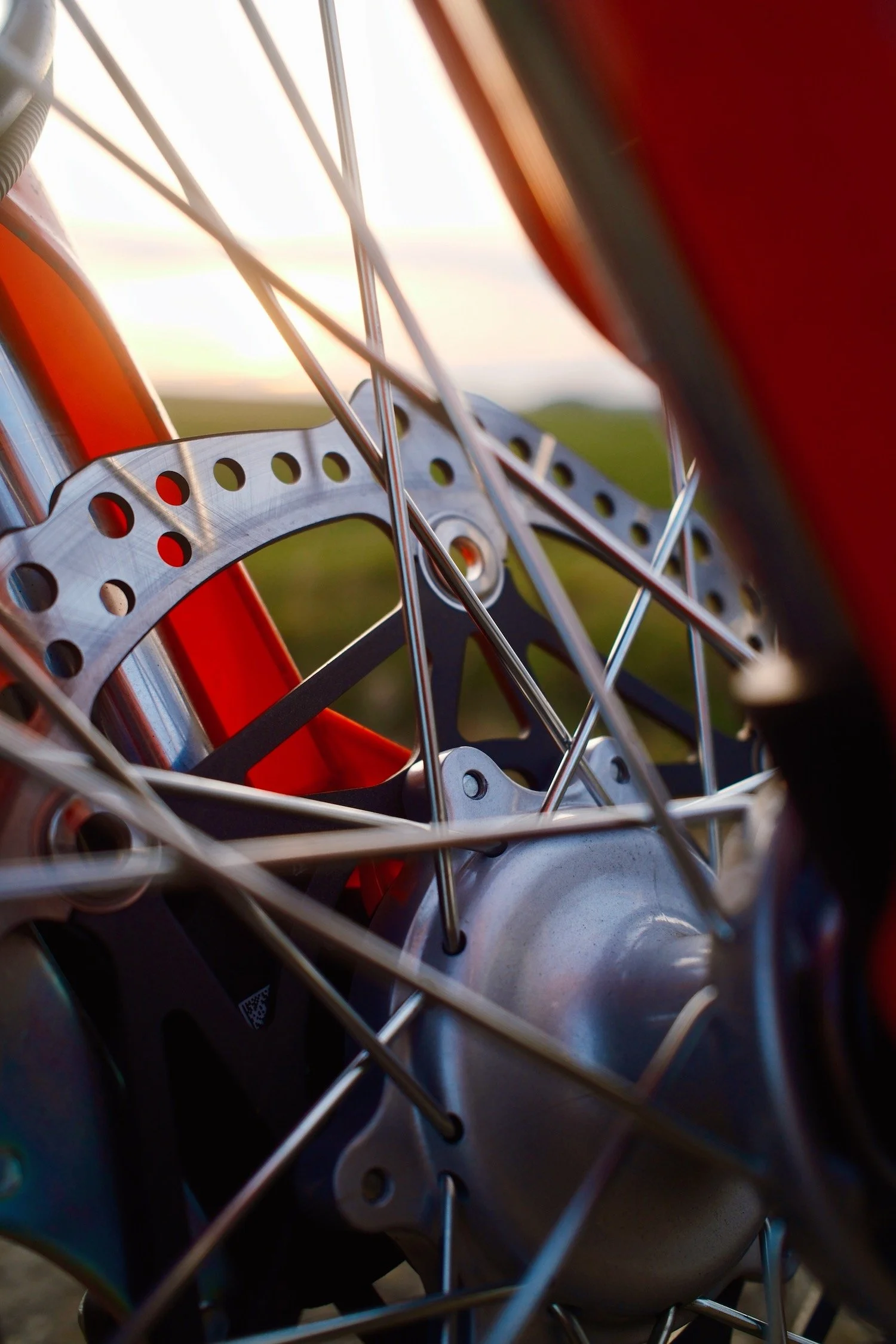  Detailbild einer Bremsscheibe eines Honda-Motorrads (CRF 300 Rally) mit Sonnenuntergang im Hintergrund. 