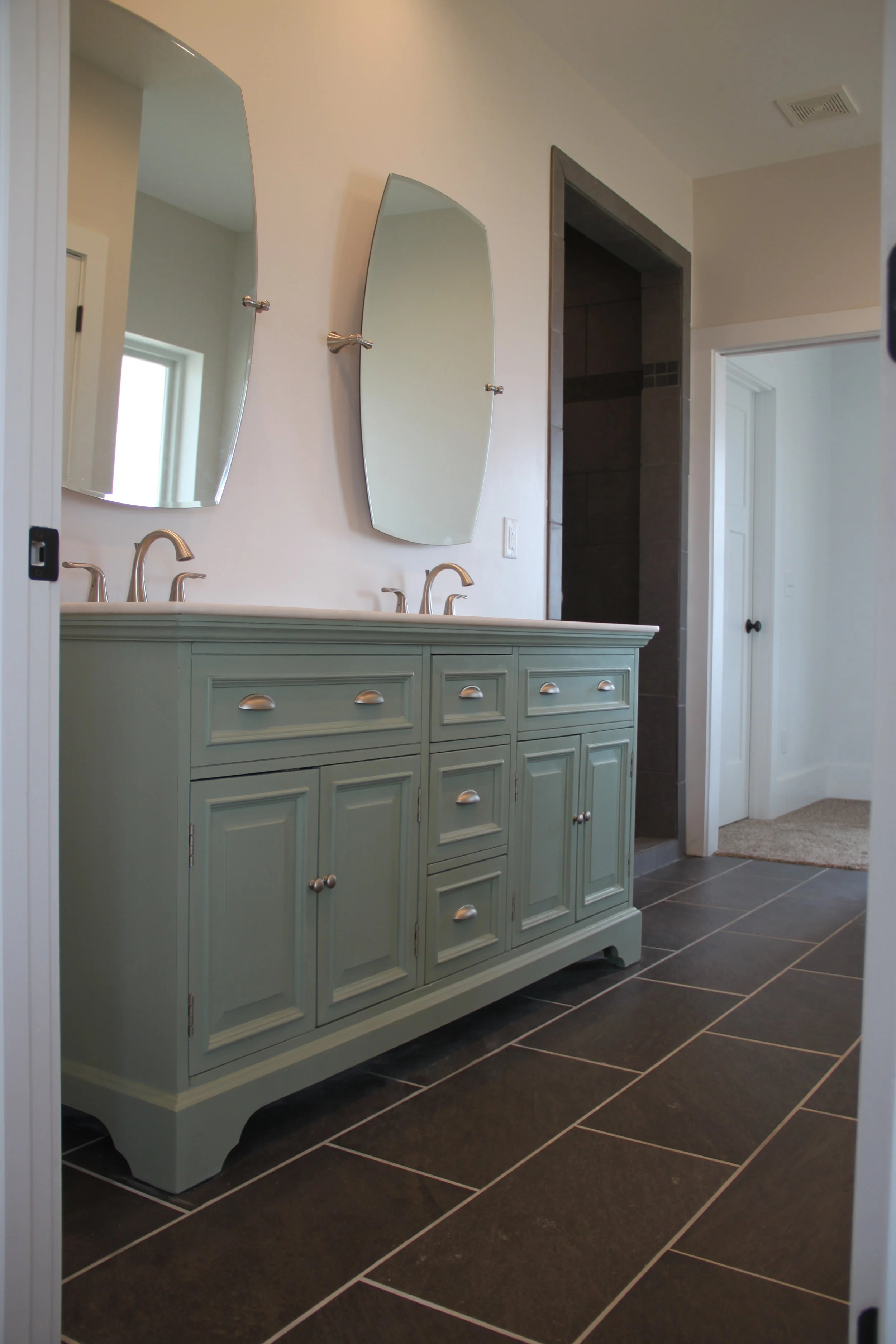 The Master Bath has a soaker tub and a shower with multiple shower heads. The beautiful charcoal tile is accented with the mint green double vanity.