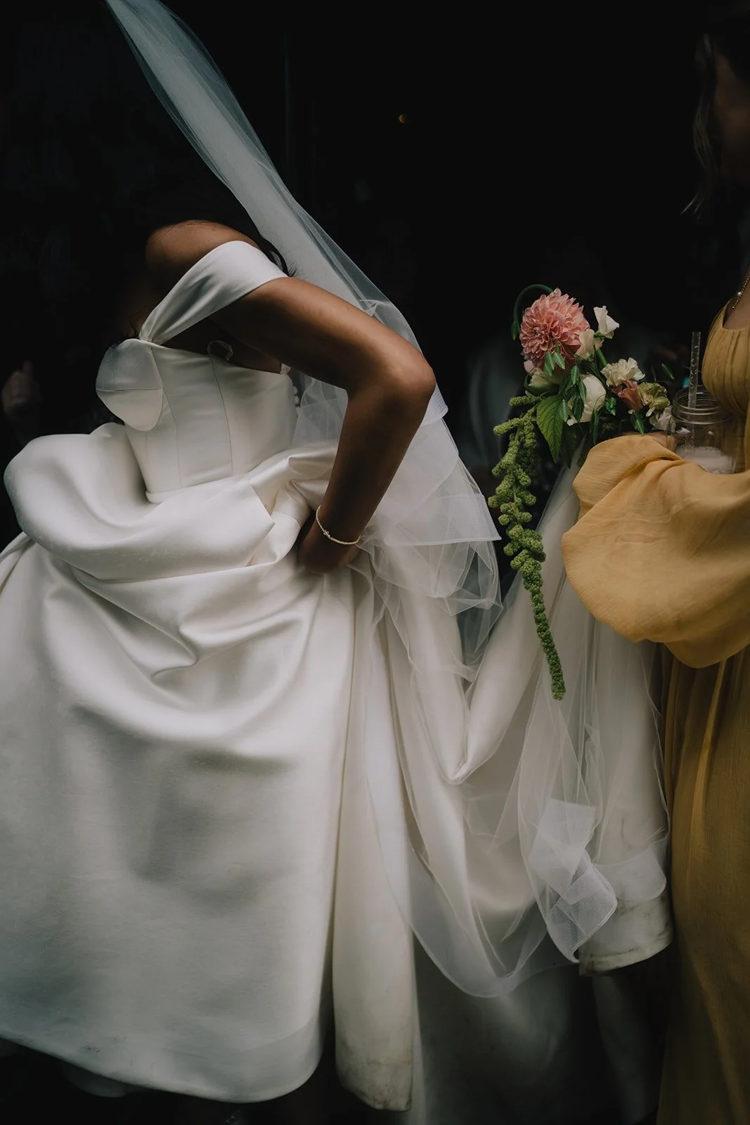 A bride in a white wedding gown adjusting her dress at a wedding reception.