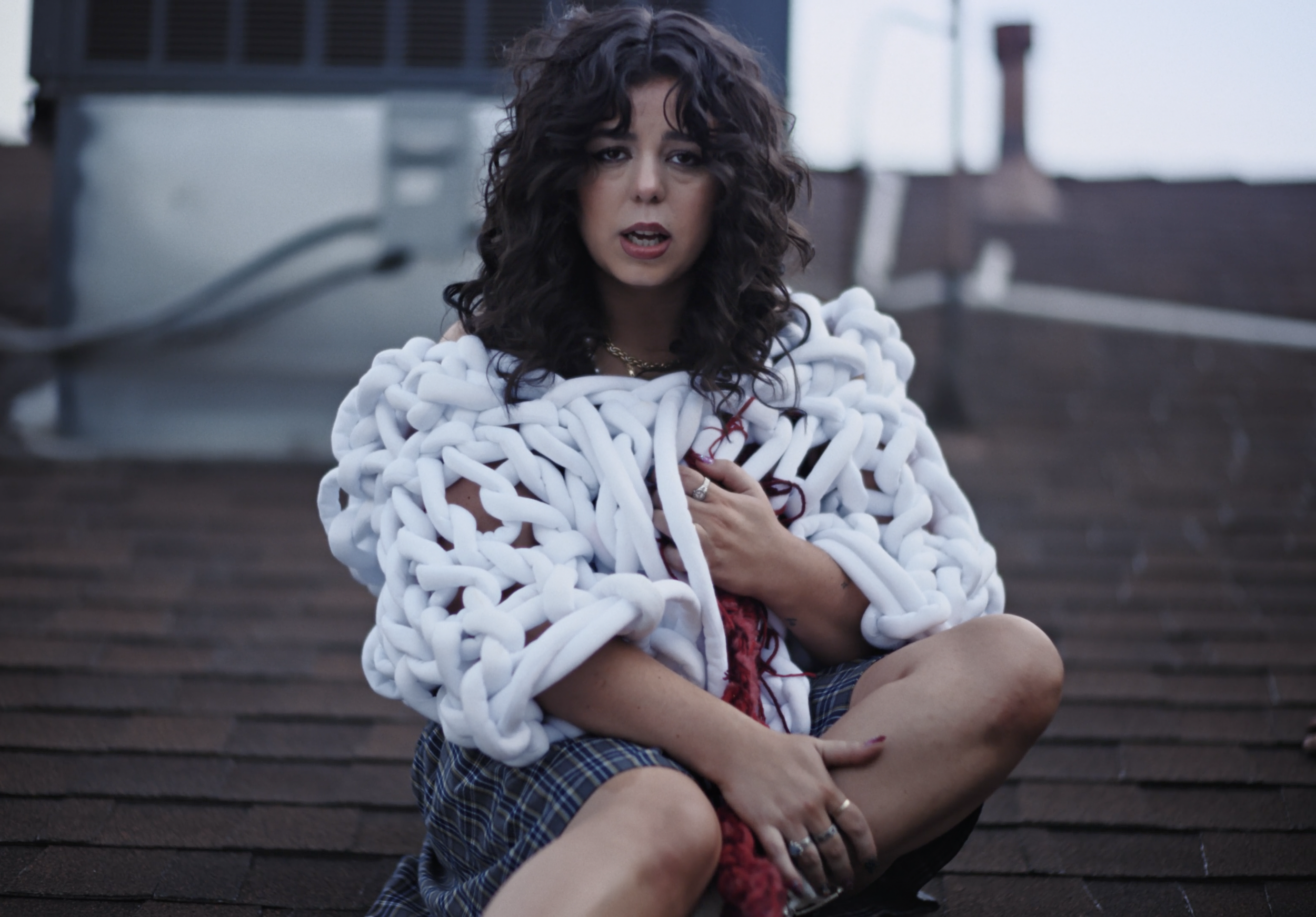 Alicia Creti on a rooftop wrapped in sculptural white knitwear for Merry Go Round