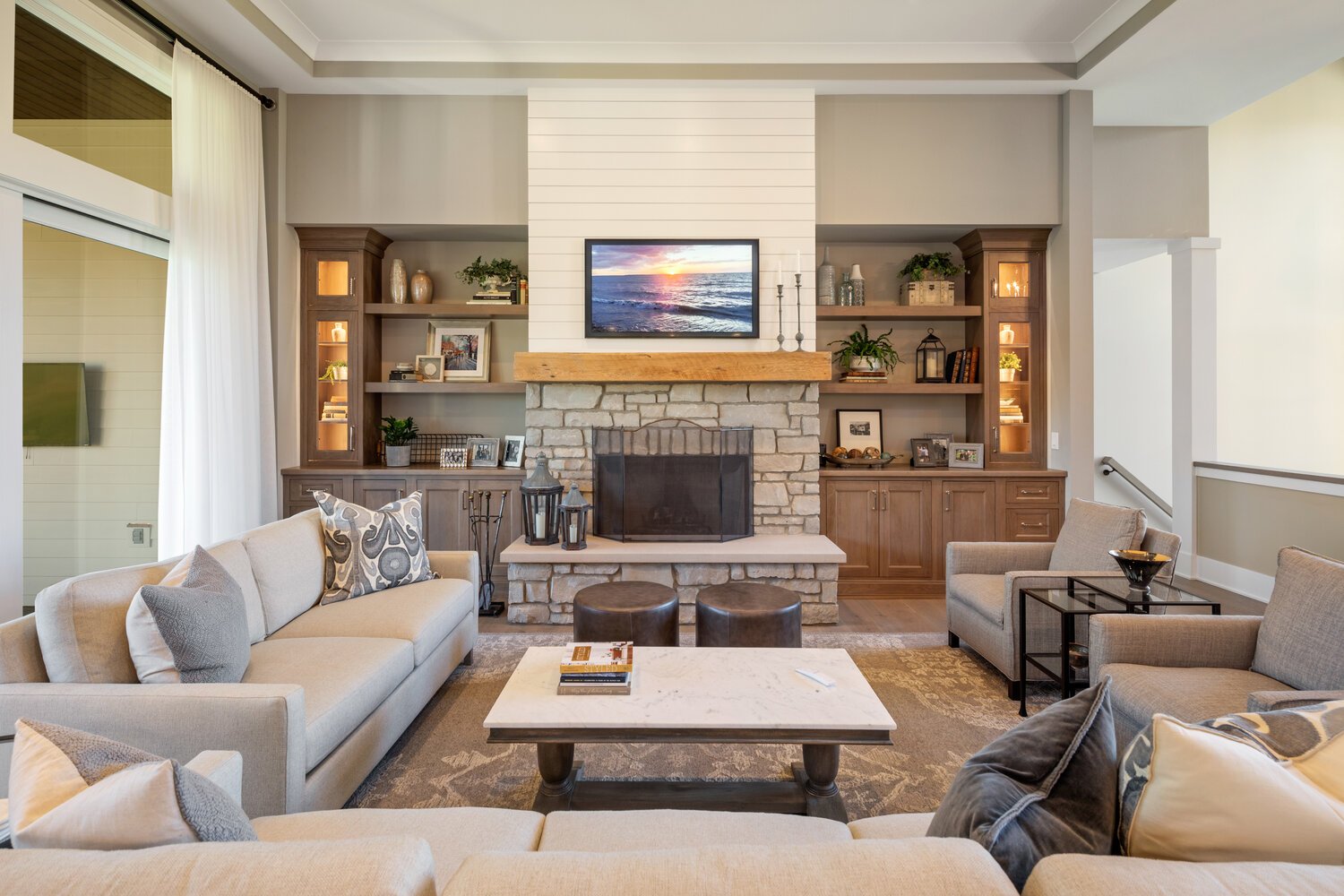 A cozy living room with a stone fireplace, built-in wooden shelving units, plush sofas, and stylish decor accents creating a welcoming atmosphere.