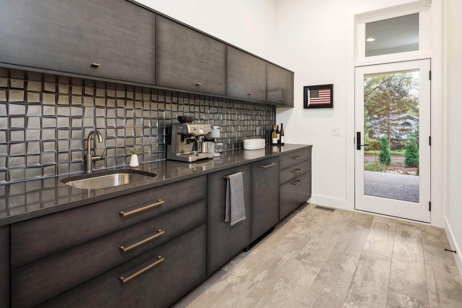 Contemporary kitchen with dark cabinets, stainless steel appliances, and view of backyard through door