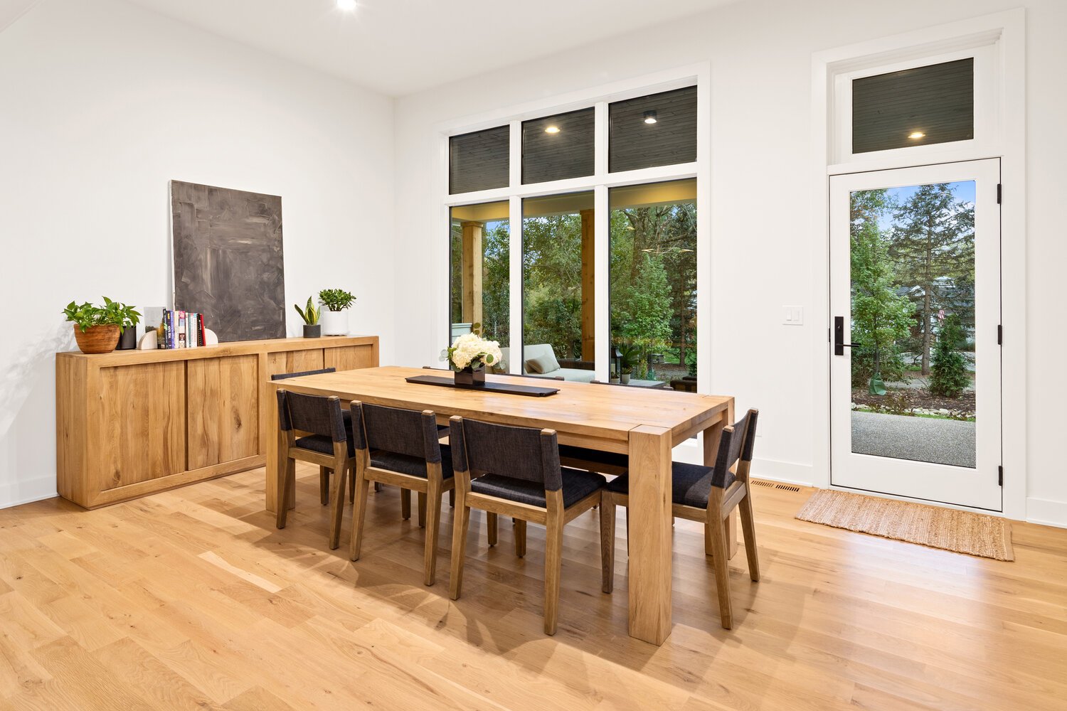 Dining area with wood table, sideboard, and large windows overlooking trees