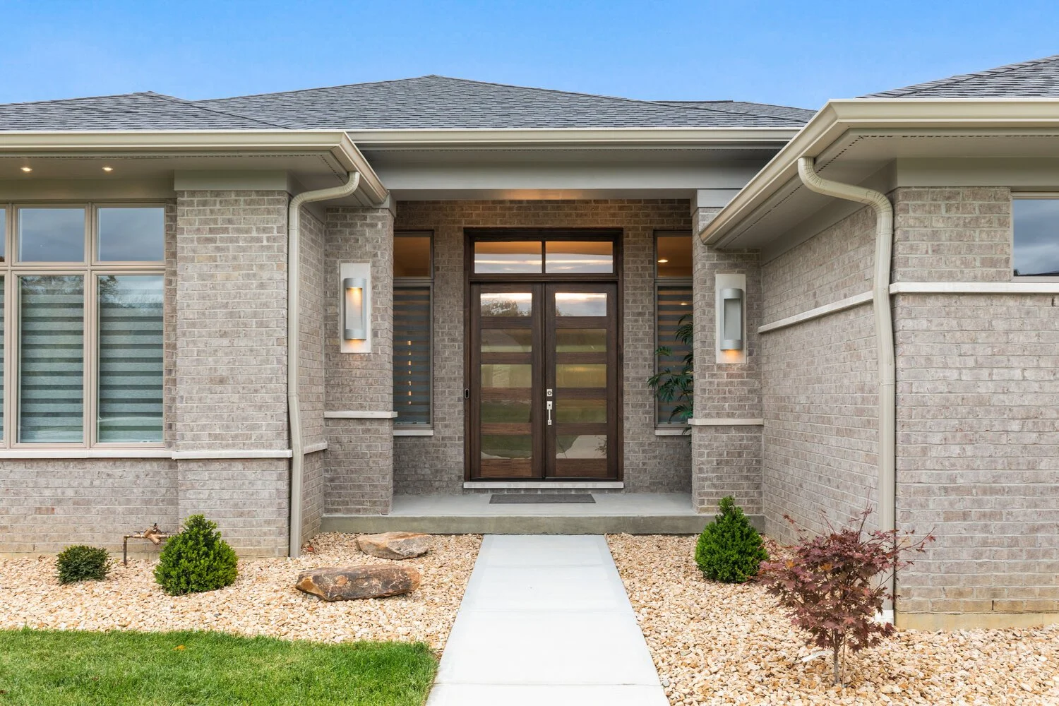 Front exterior of home with brick facade, arched entryway, and landscaped front yard with pavers.