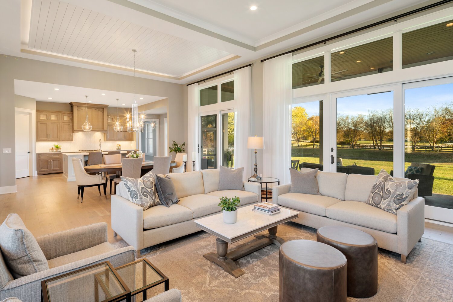 An open-concept living area with a chef's kitchen, dining area, and a sitting room overlooking a scenic outdoor view through large windows framing the landscape.