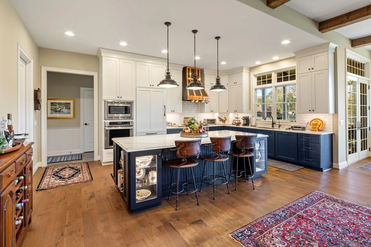 Transitional in style, the white and navy cabinets command attention extending to the ten-foot ceiling in the kitchen