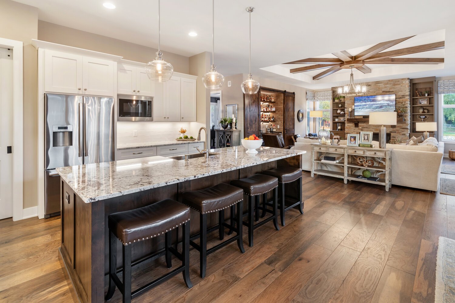 Open concept kitchen with granite countertops, stainless steel appliances, and a large island with bar seating.