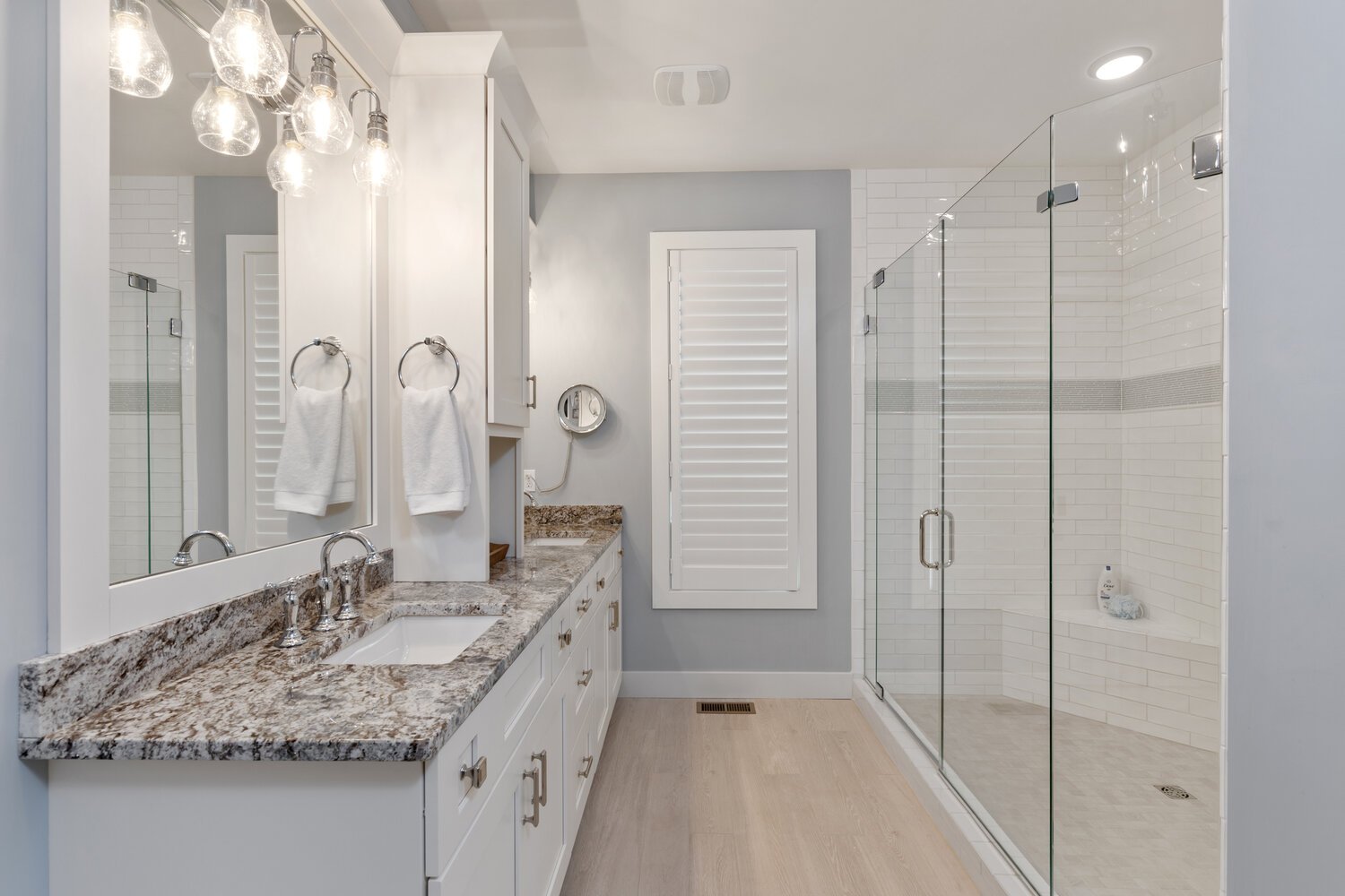 Luxurious bathroom with marble countertops, glass shower, and elegant lighting fixtures.