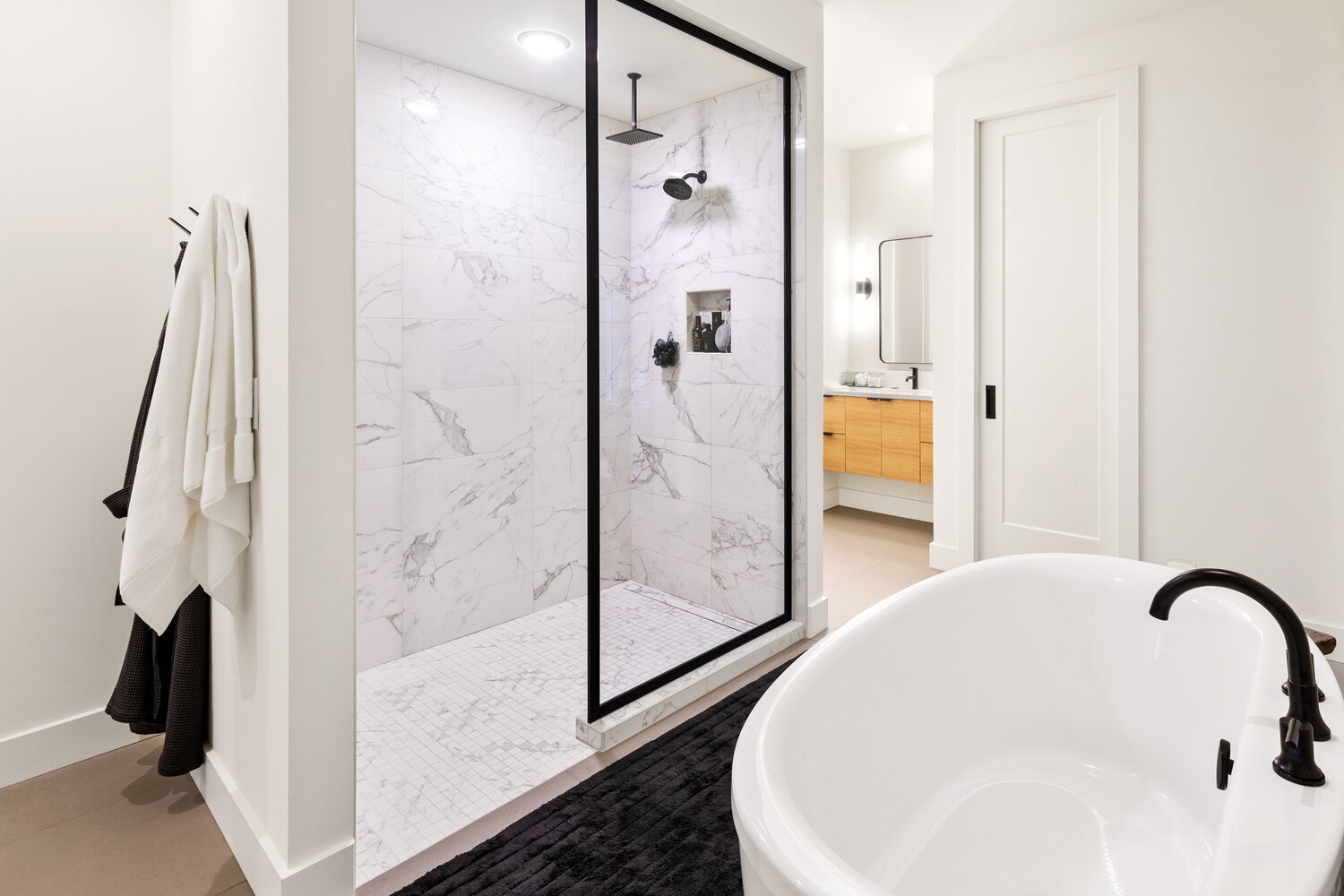 Luxurious master bathroom with marble shower, freestanding tub, and wood vanity