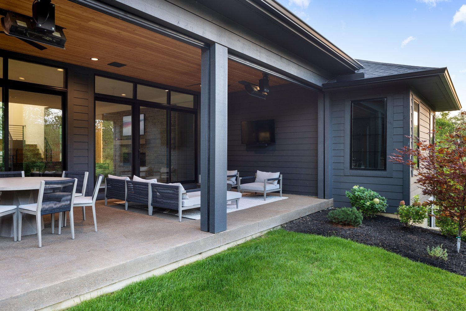 Outdoor living area with a covered patio, comfortable seating, and a landscaped yard.