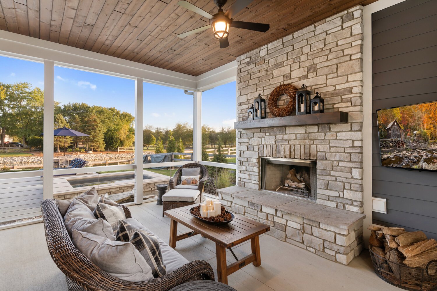 Cozy outdoor living space with stone fireplace, seating area, and picturesque view.