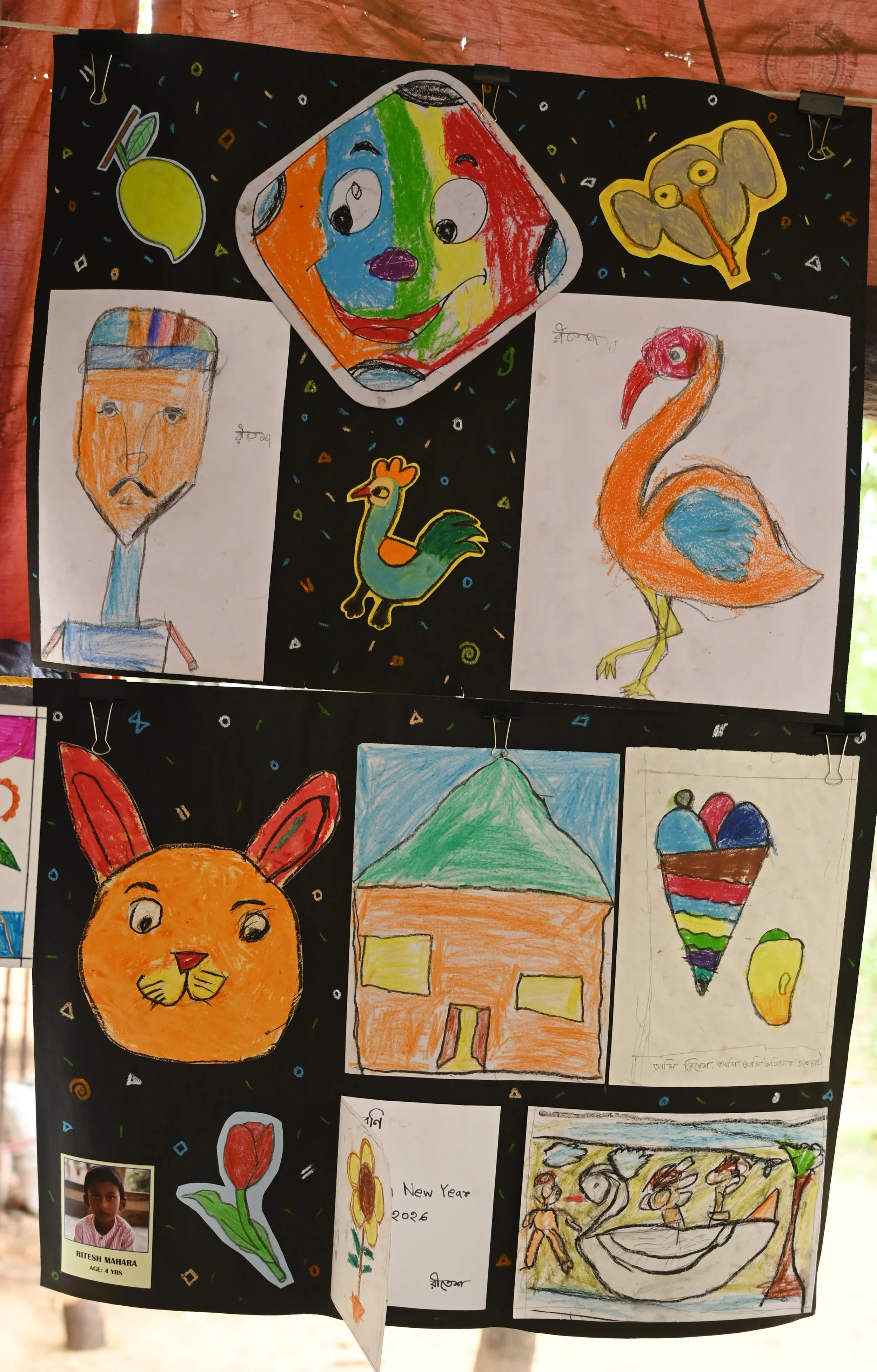Collection of children's drawings on black paper, including a colorful smiling face, an elephant, a bird, a house, a bunny, a heart, and a flower, with a child's photo and name at the bottom.