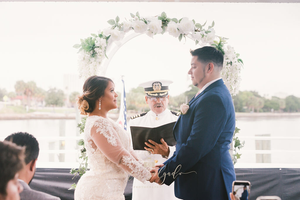 bride-and-groom-holding-hands, bride-and-groom-during-ceremony, wedding-ceremony, wedding-officiant, wedding-archway, wedding-on-a-boat