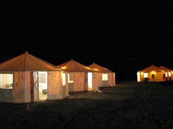 Fire camp yurts illuminated at night.