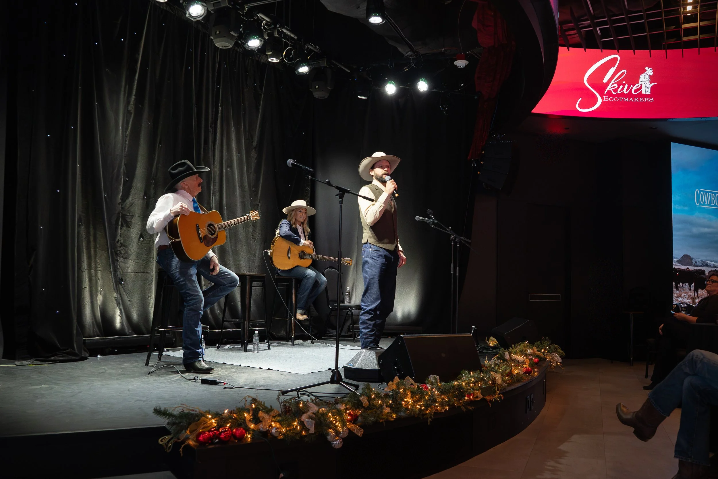 Musician R.W. Hampton, poet Jake Riley, and musician Trinity Seely perform onstage