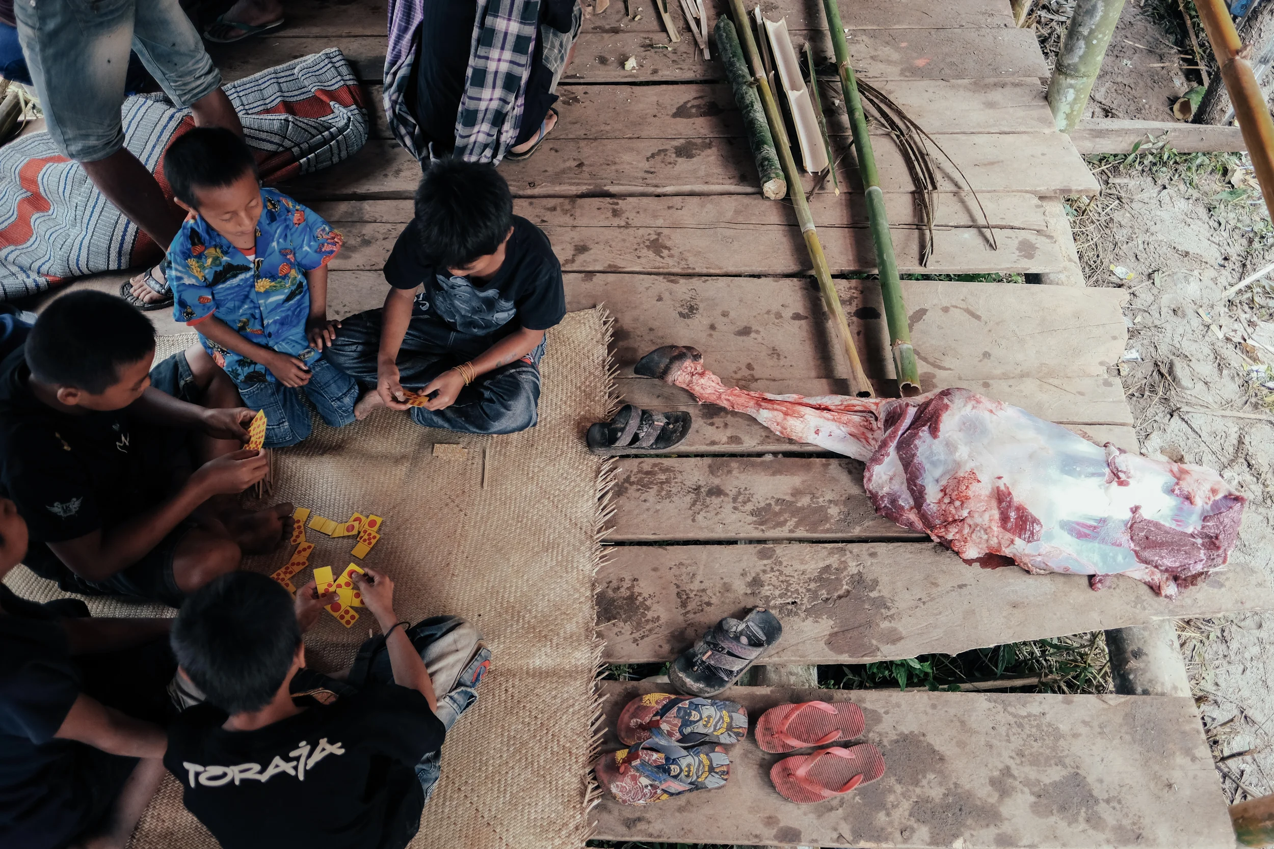 Children play in makeshift structures around the killing ground as a leg of buffalo meat is left for their family.