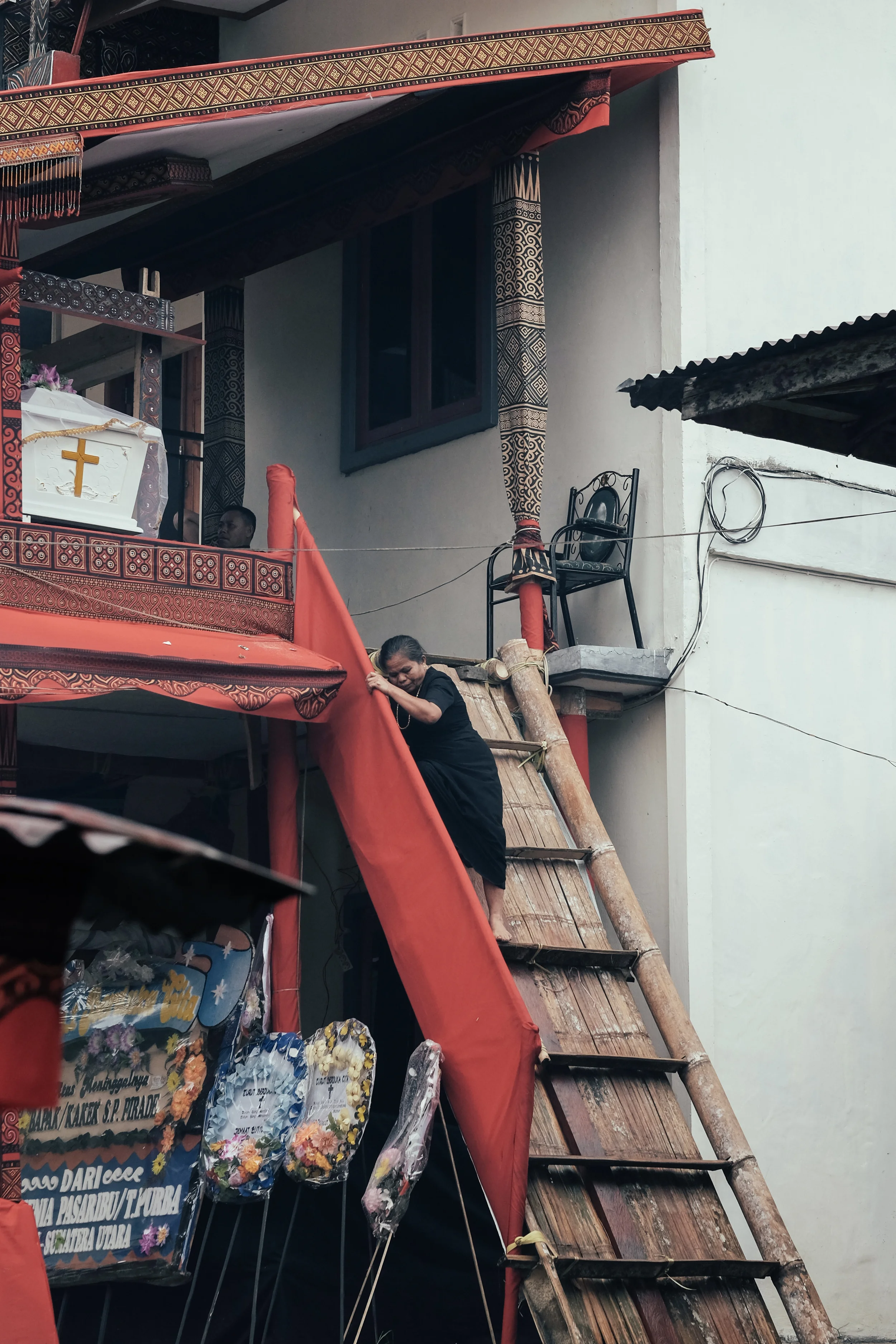 A woman clambers down from where the coffin is placed. The elevation of the coffin determines the social status of the deceased.