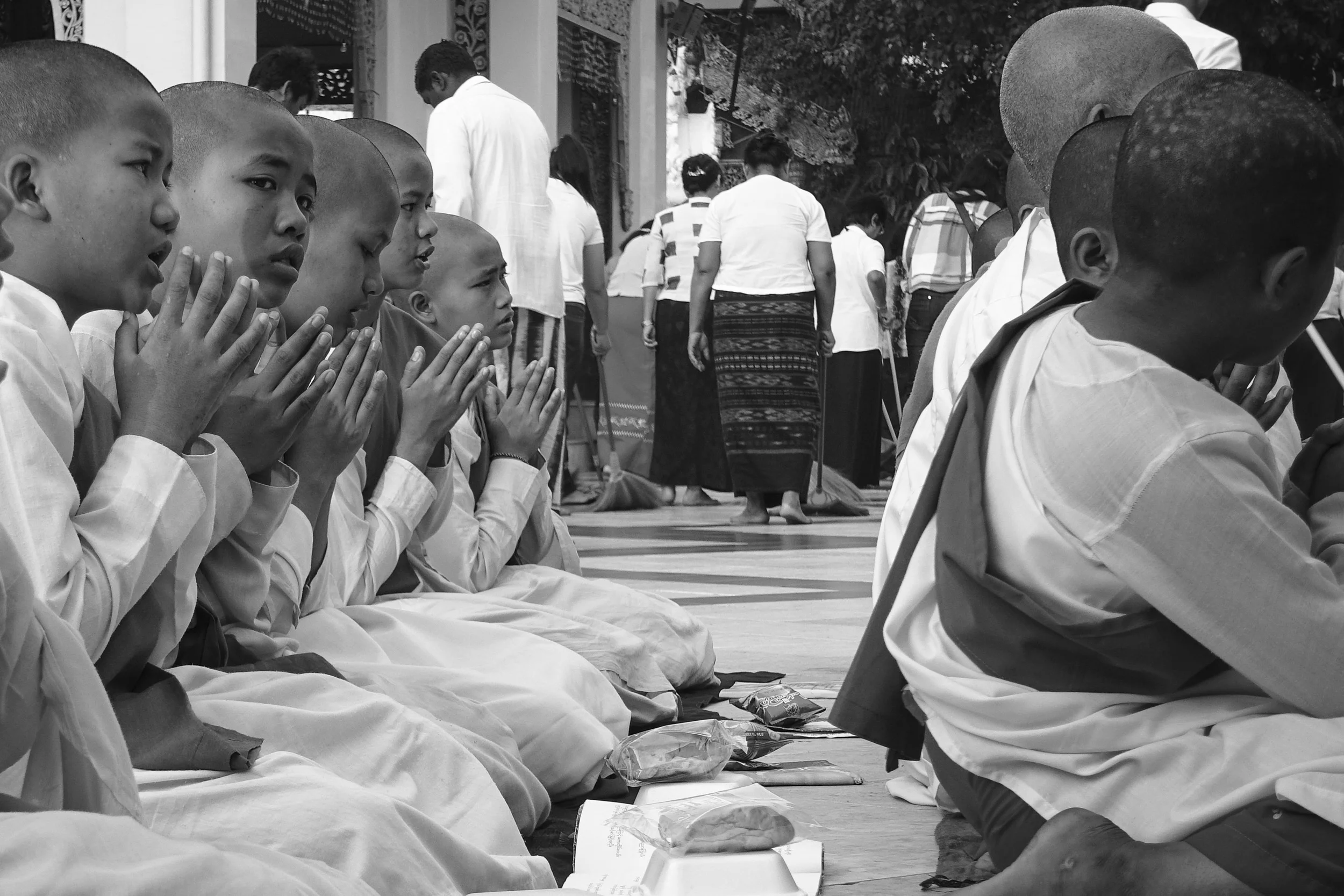 Young monks move around the central pagoda structure, singing hymns and collecting alms.