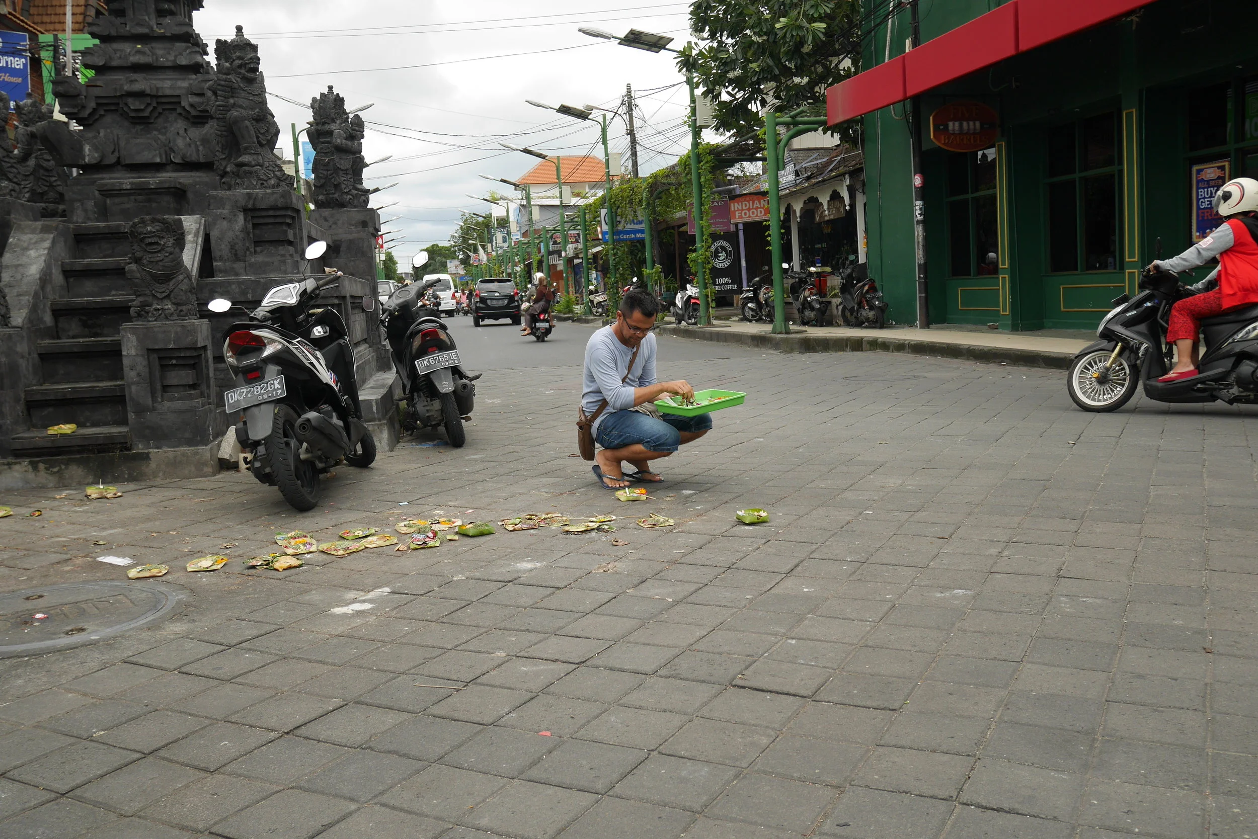 A man offers prayers on the road, oblivious to the bustling incoming traffic.