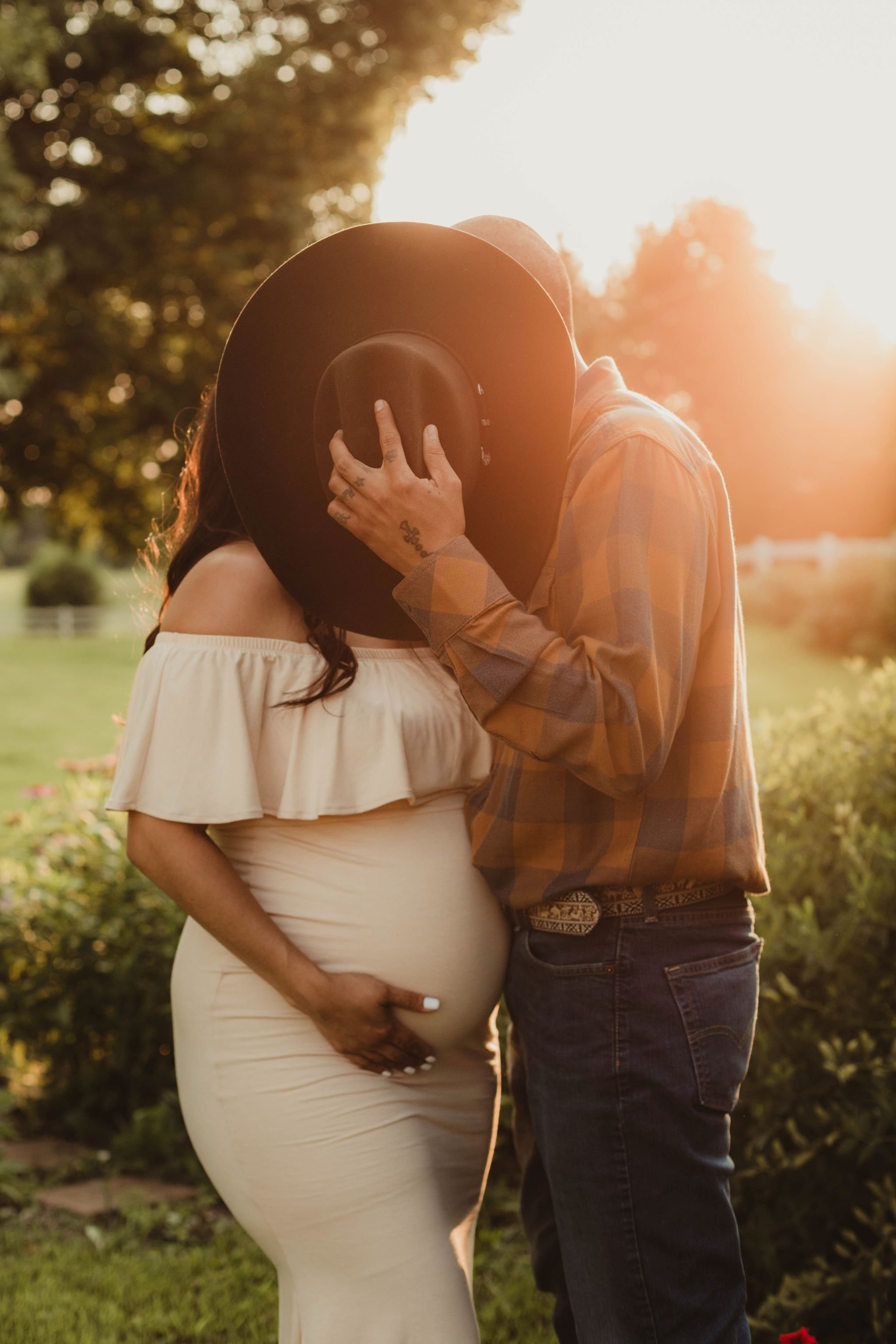 husband_kisses_pregnant_wife_behind_hat.jpg