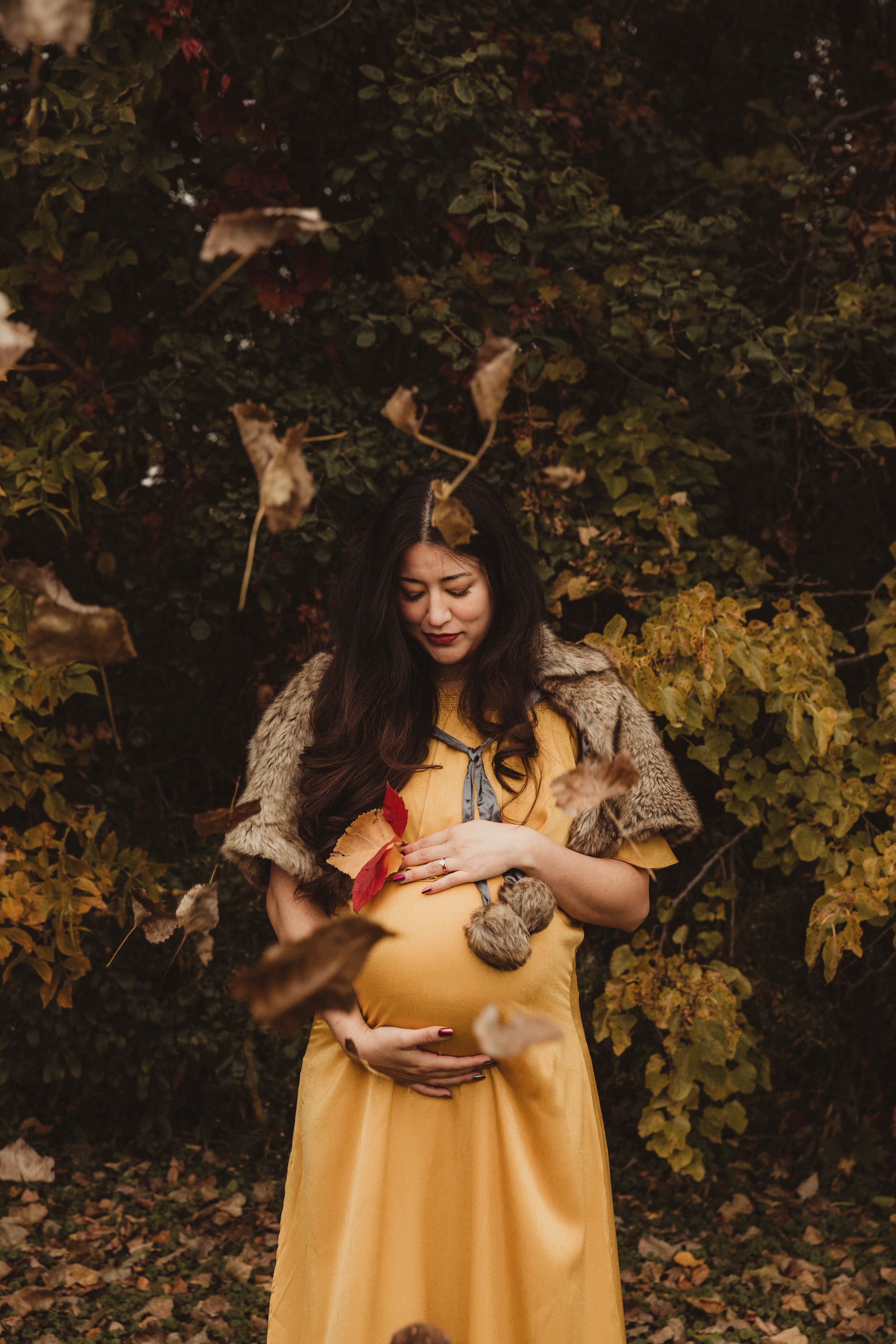 pregnant_mom_looks_at_belly_fall_leaves_maternity_photoshoot.jpg.jpg