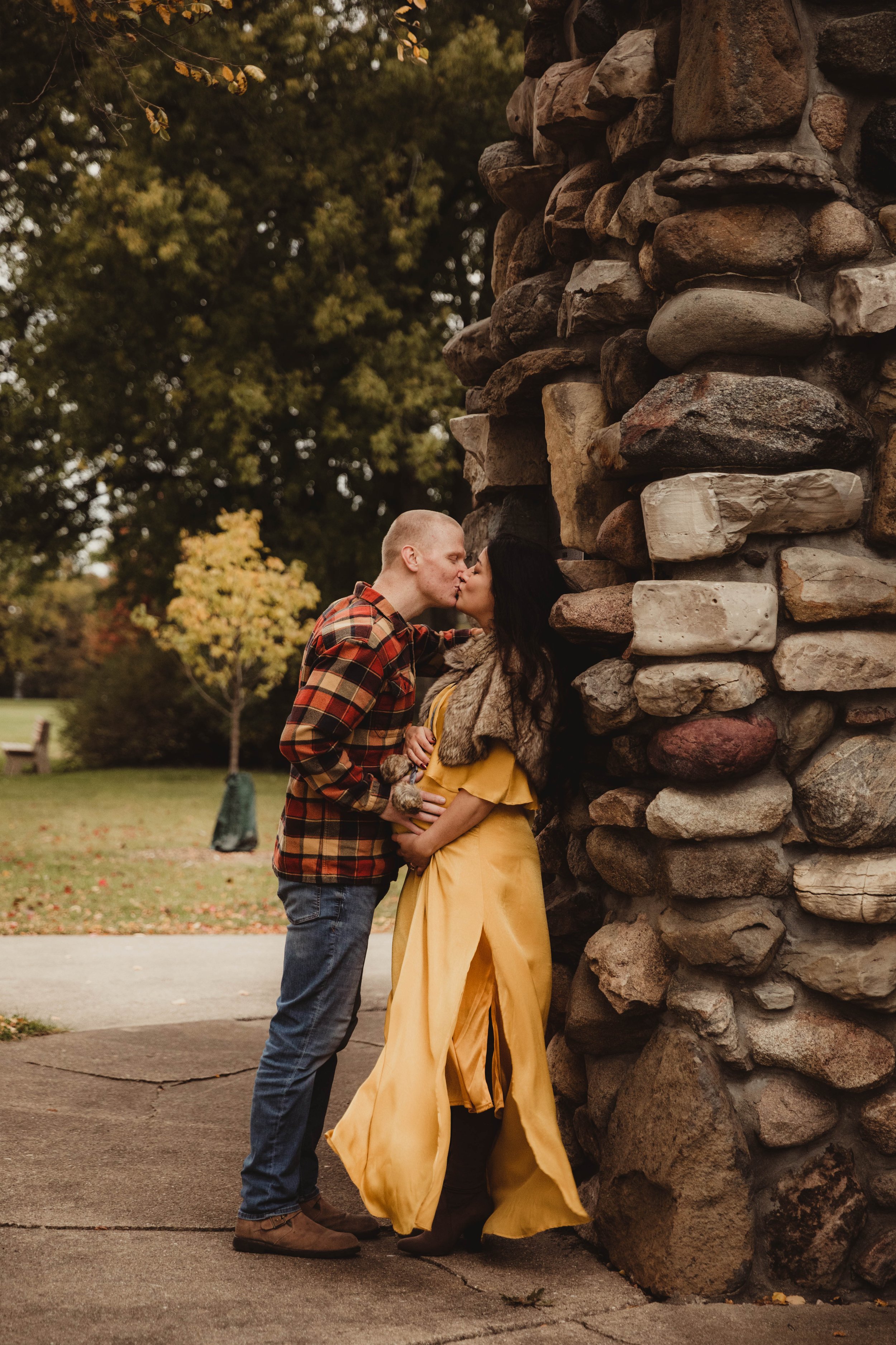 husband_kisses_pregnant_wife_against_stone_wall_at_sycamore_park.jpg.jpg