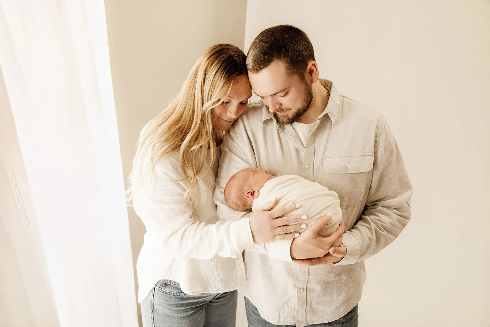 newborn_parents_smile_at_baby_during_photoshoot