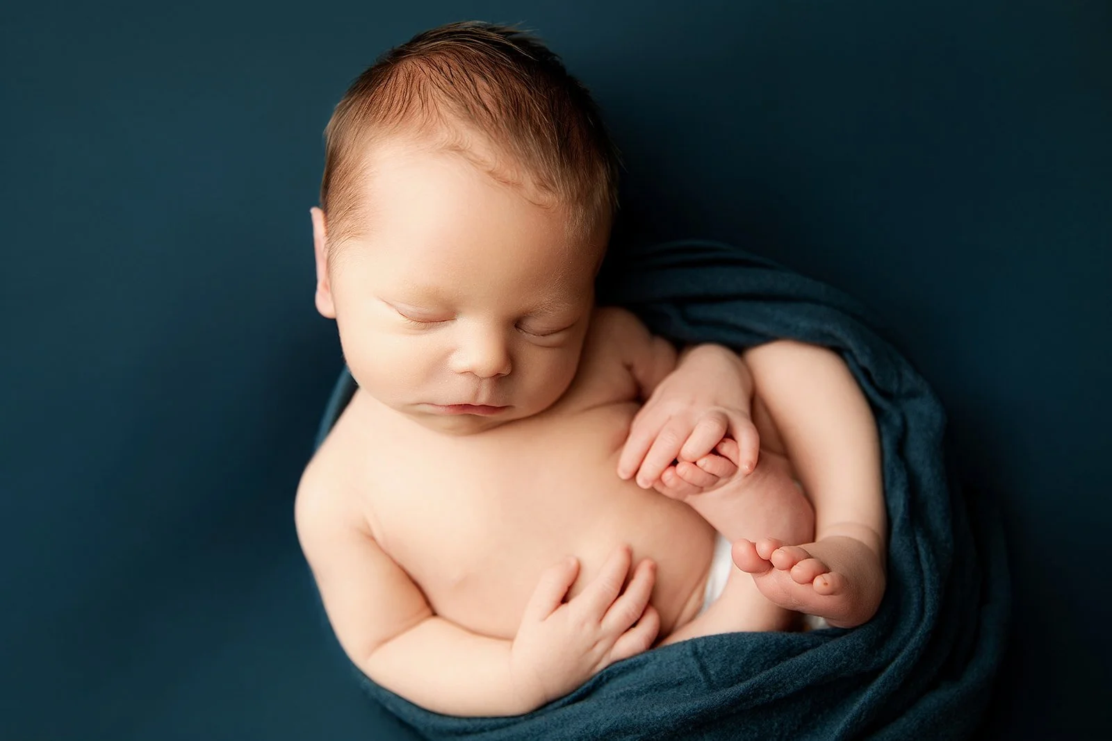 newborn_boy_sleeps_on_blue_backdrop