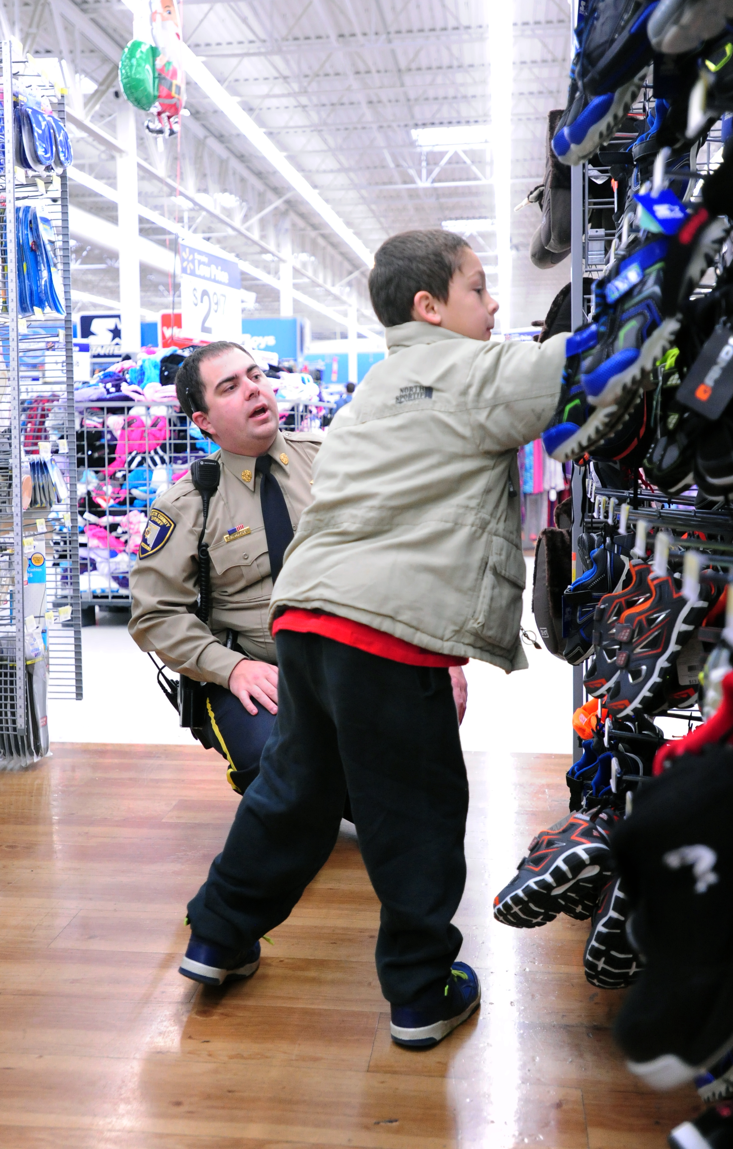 NICK INGRAM/Citizen photo Platte County Sheriff’s Office deputy Richard Mayse, left, helps pick out shoes with Jackson Schafer, 7, at a Wal-Mart Supercenter on Saturday, Dec. 3 in Kansas City, Mo.