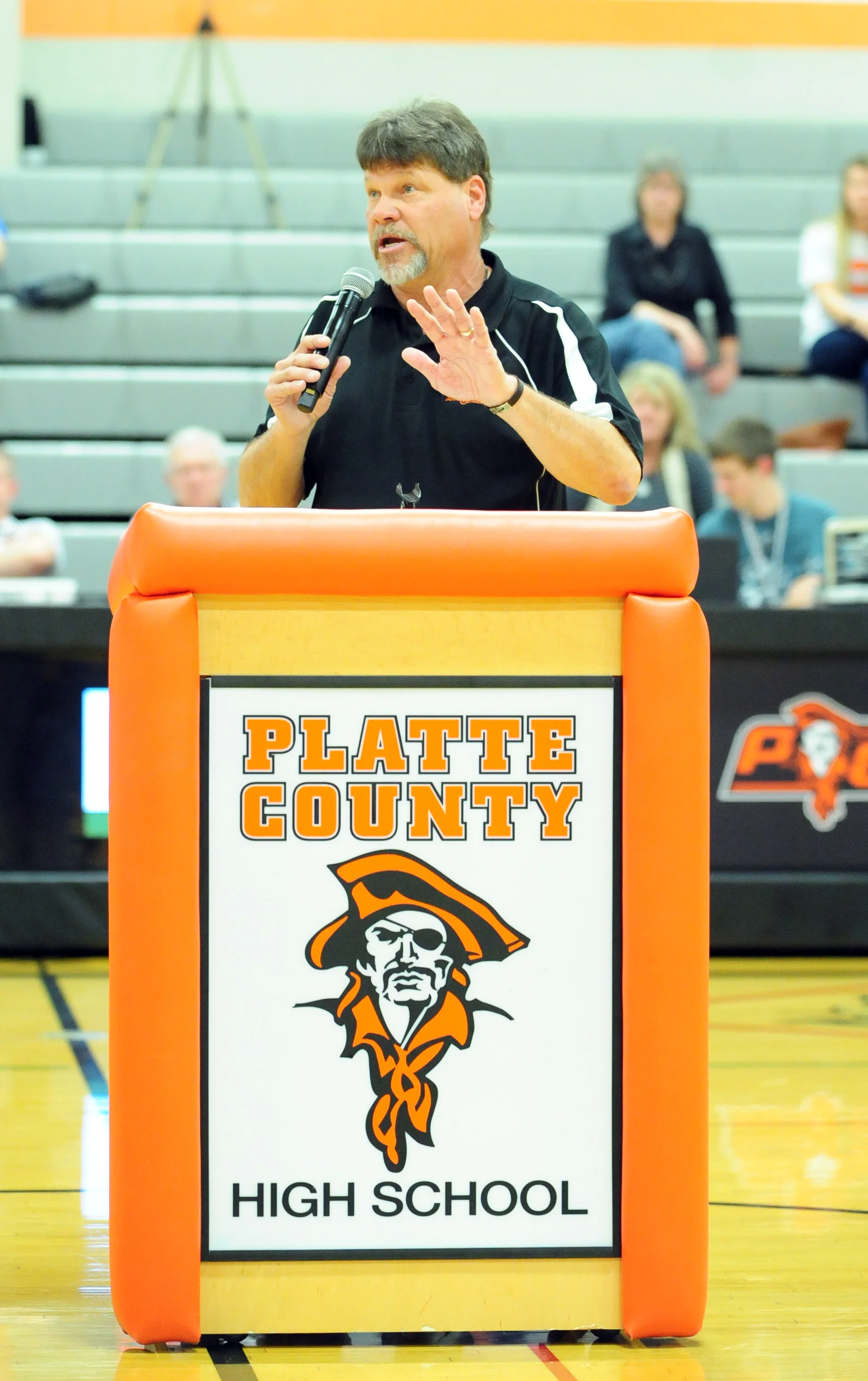 NICK INGRAM/Citizen photo Former Platte County High School coach and athletic director Greg Jaros speaks during the Pirate Hall of Fame induction ceremony on Friday, Feb. 17 at Platte County High School. BOTTOM: Former coach Jan Patterson, right, hugs Jaros.