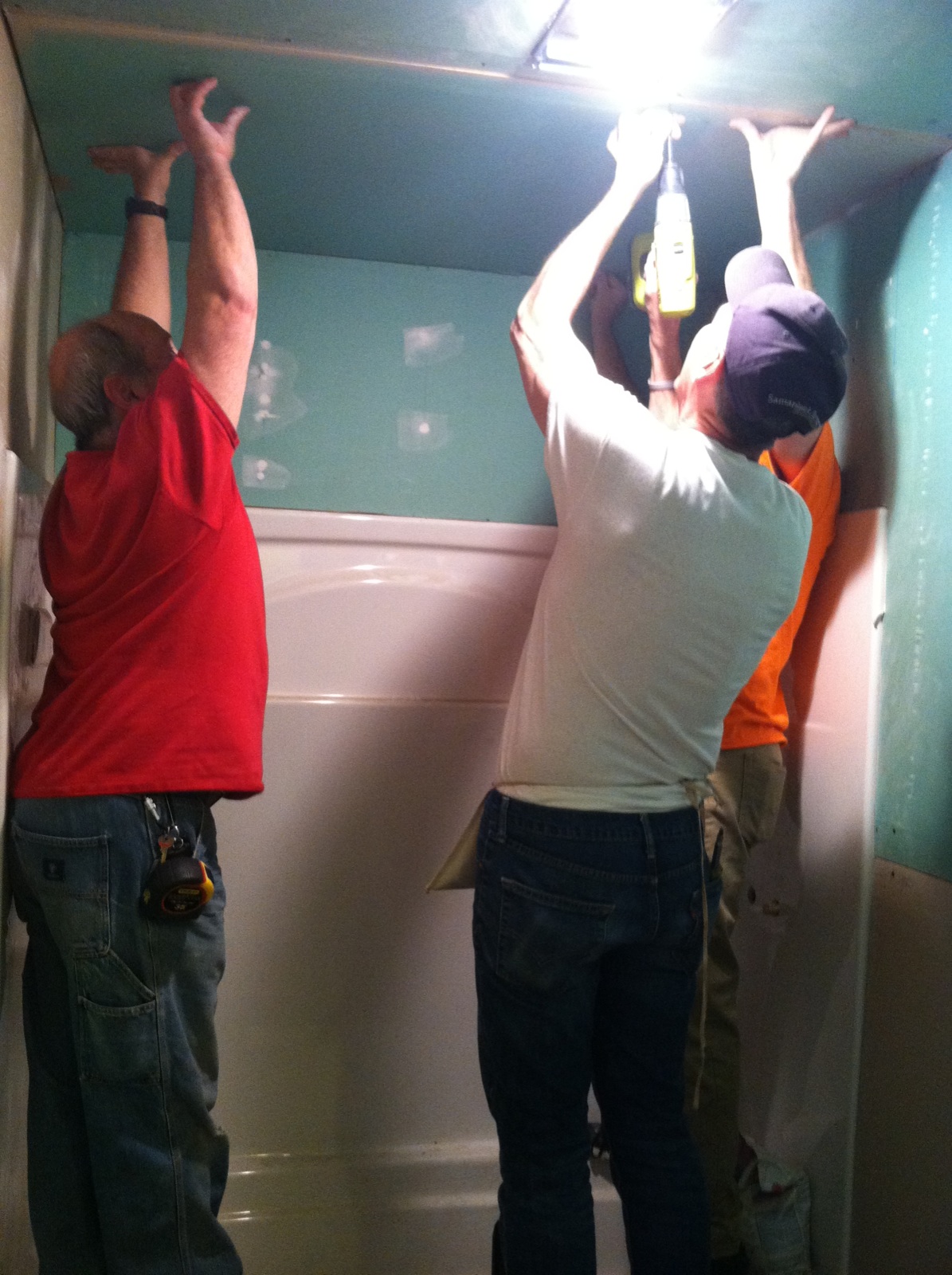 Aaron, Terry and Jim install green board in the bathroom. Walls and ceiling were installed.