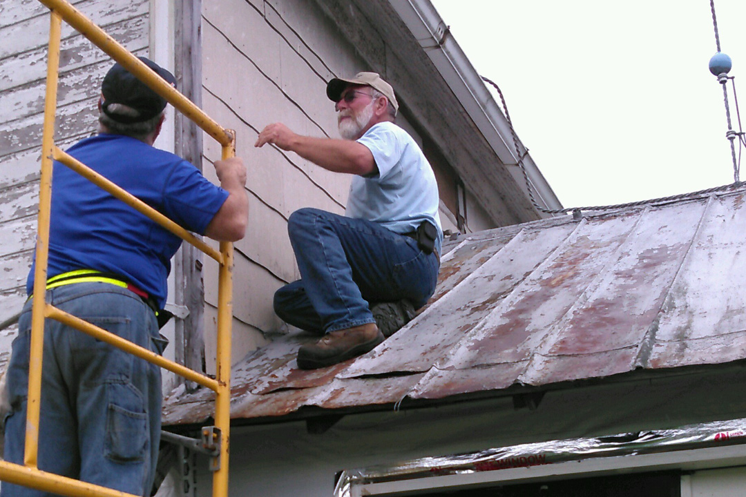 Ben and Jim try to figure out how to install the house wrap on the second story.