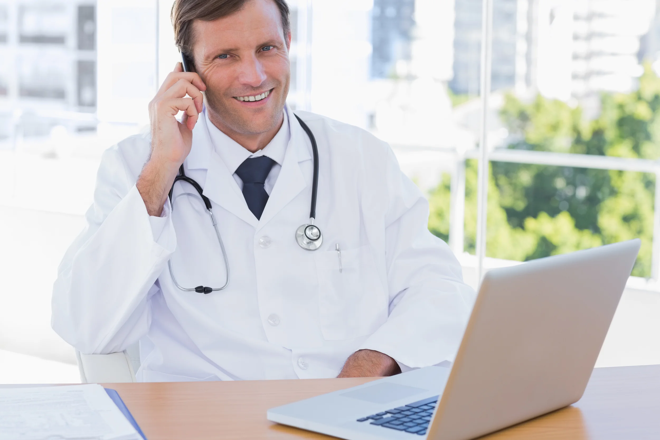 Happy doctor phoning in his office