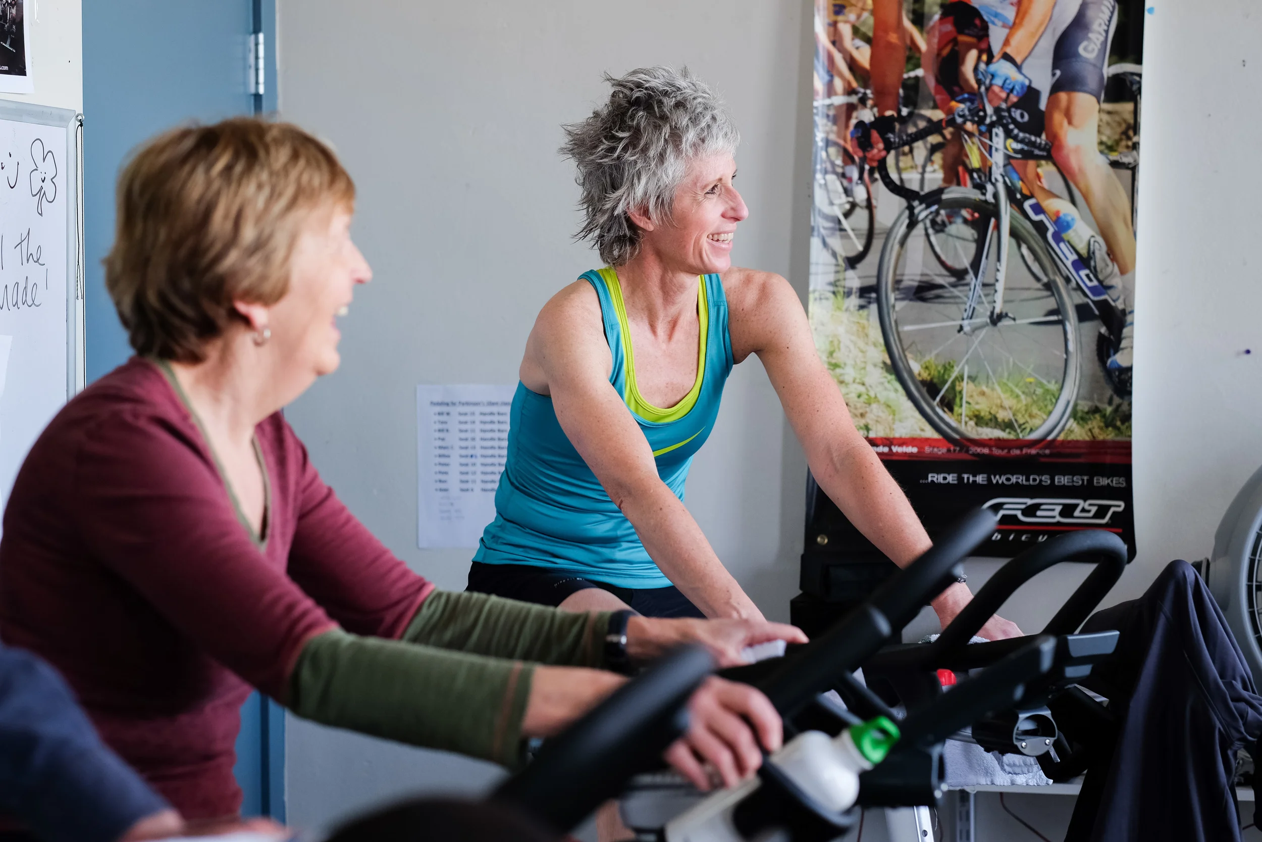 TRACY DHIEL, AN INSTRUCTOR AND LEADER OF THE PEDALING FOR PARKINSON’S CLASS AT THE YMCA, CHATS WITH PARTICIPANTS DURING THE HOUR BIKE RIDE. STUDIES HAVE SHOWN THAT SPIN CLASSES LIKE THIS ONE CAN HELP REDUCE SYMPTOMS FOR PARKINSON’S BY AROUND 35 PERCENT, ACCORDING TO THE YMCA. For Klipsun Magazine